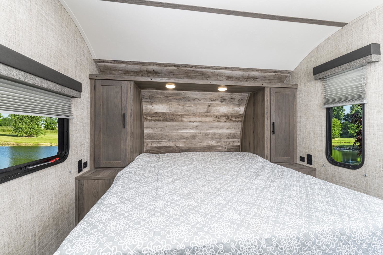 Comfortable RV rental bedroom featuring a queen bed, warm wood accents, and scenic lake views from the windows.. Gulf Stream kingsport 2021