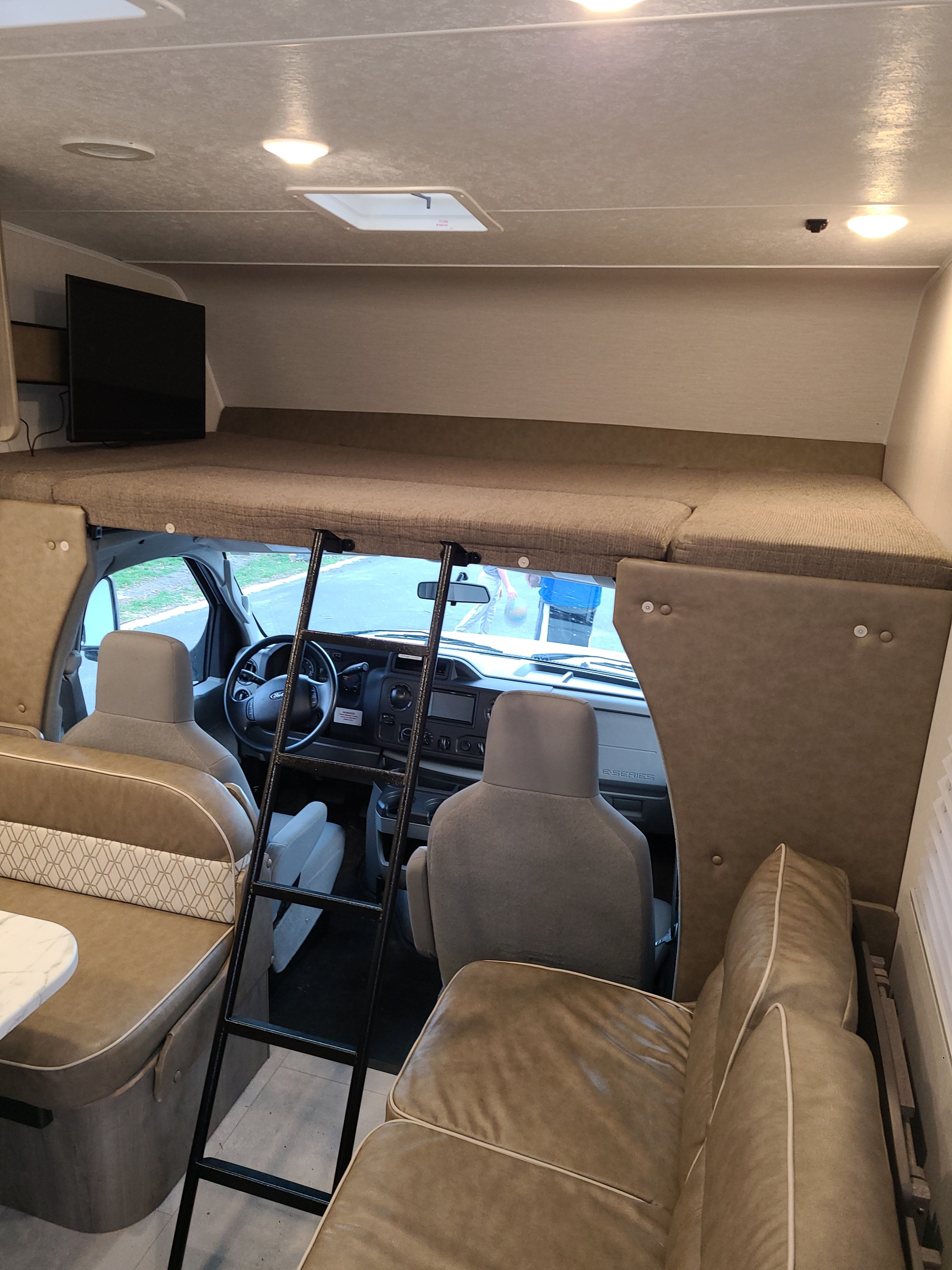 RV rental interior showing the large cab-over sleeping area with TV, ladder, and front cabin view.. Coachmen Freelander 2021