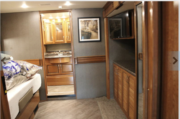 This RV rental features a comfortable bedroom area with a mounted TV & storage, connecting to a private bathroom with a vanity.. Fleetwood Pace Arrow 2018