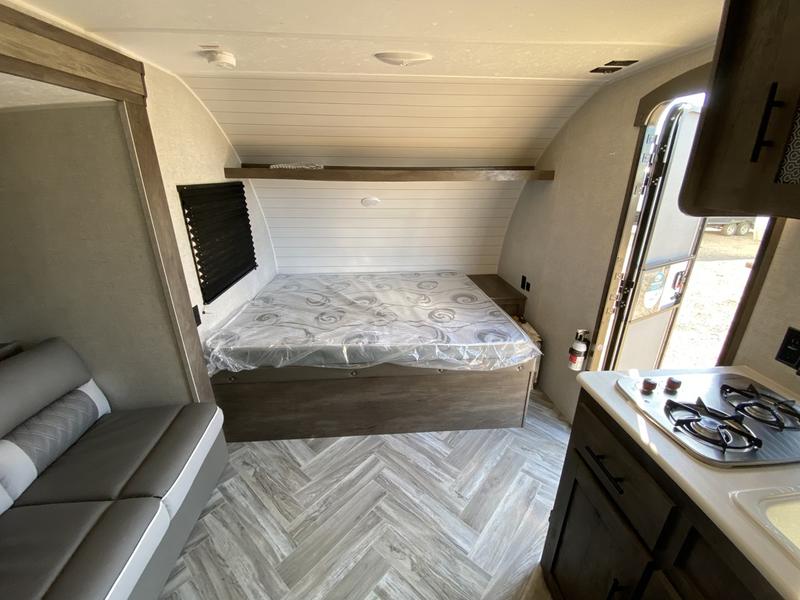 Cozy RV rental interior with a comfortable bed, compact kitchen, and sofa seating, ready for your next travel adventure.. Forest River Evo 2021