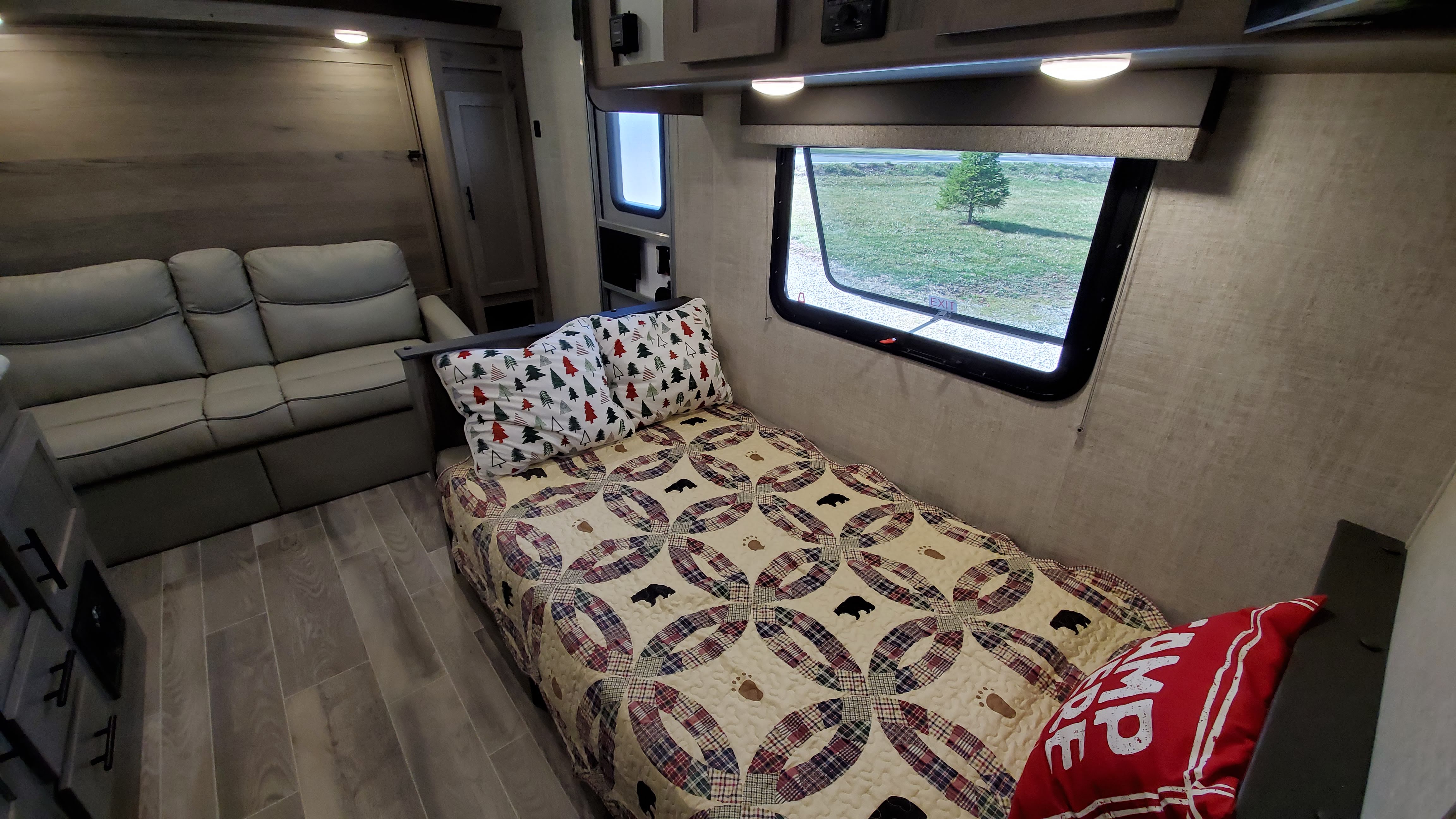 Step inside this cozy RV rental, featuring a comfortable sofa, single bed with bear-themed quilt, and scenic window view.. Gulf Stream Ameri-Lite 2021