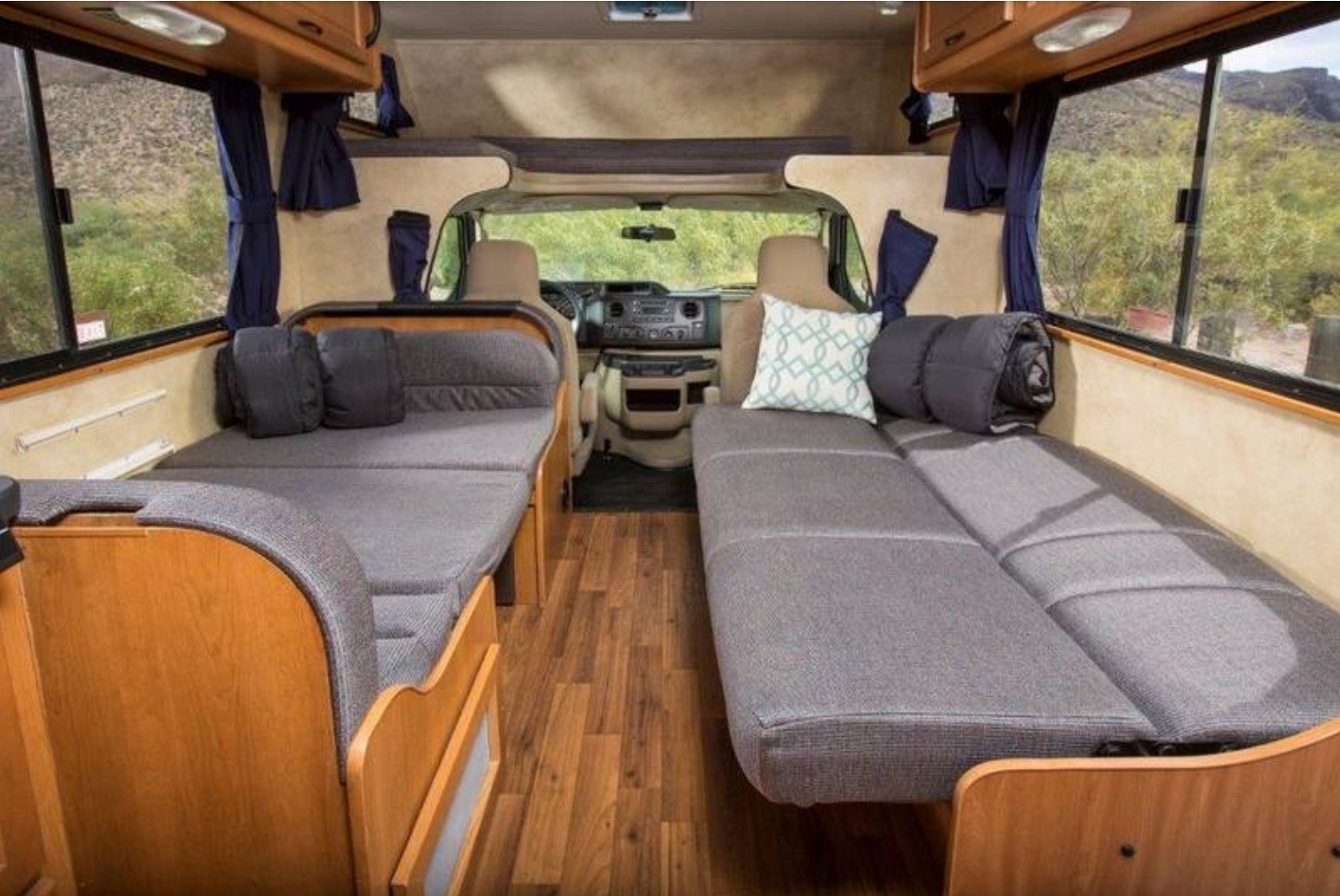 RV rental interior features twin grey beds, wood accents, and large windows revealing scenic outdoor views.. Other Four Winds Majestic 2014