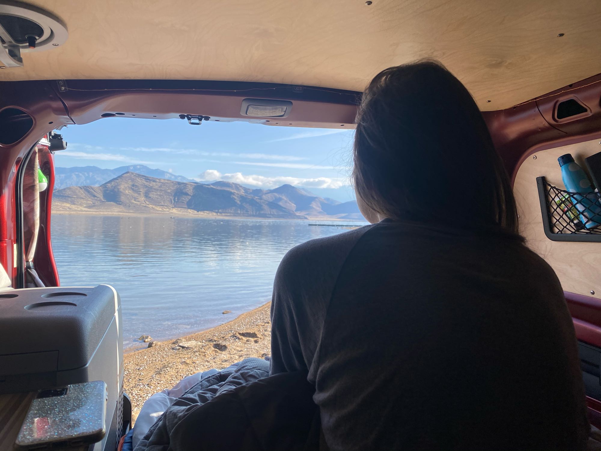 RV rental: Person enjoys a tranquil lake & mountain view from inside a camper van.. Cascade Campers Ram Promaster City 2018
