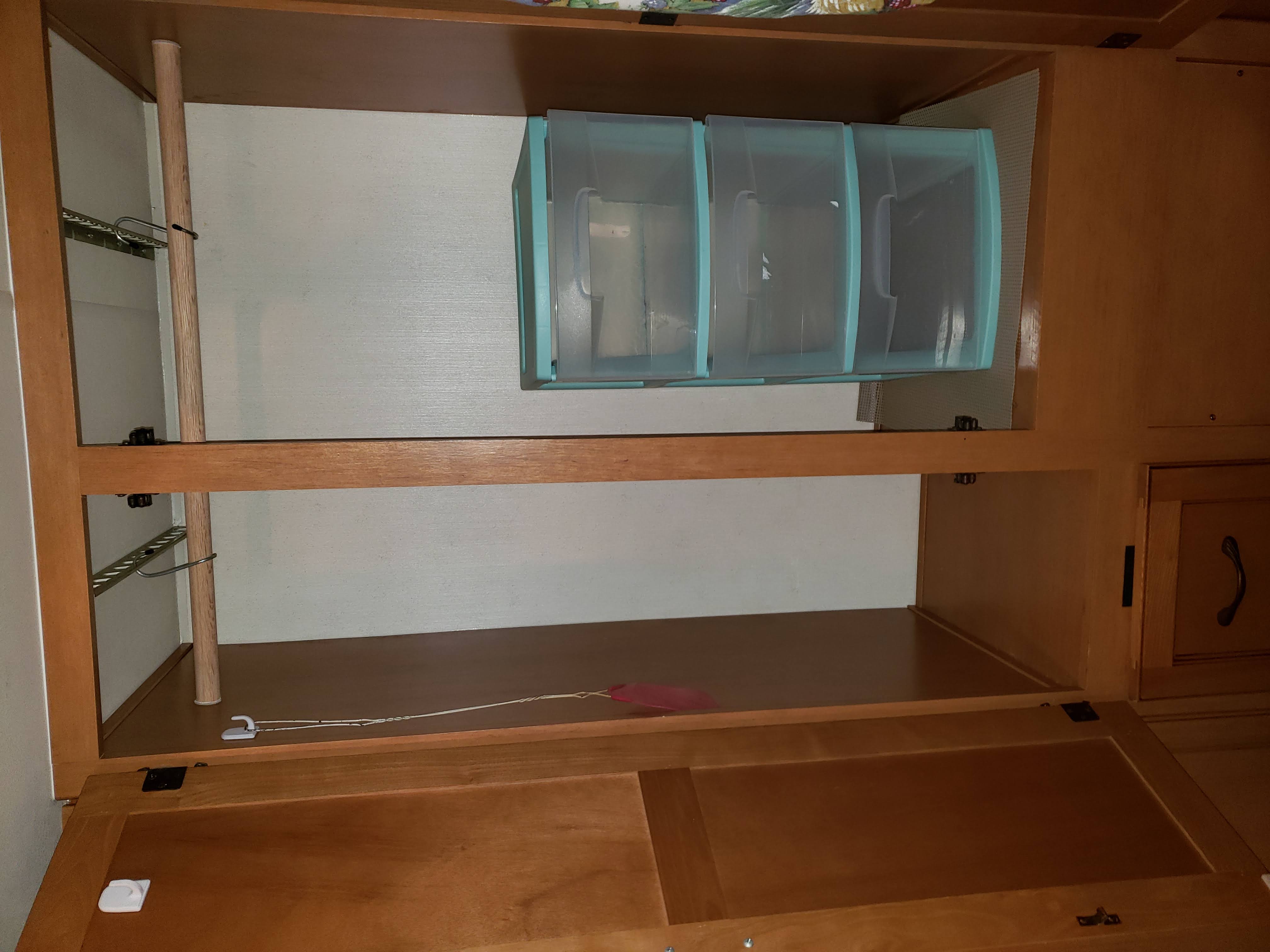 RV rental interior: Detailed view of compact storage with clear bins, shelving, and a hanging clothes rack.. Coachmen Freelander 2013