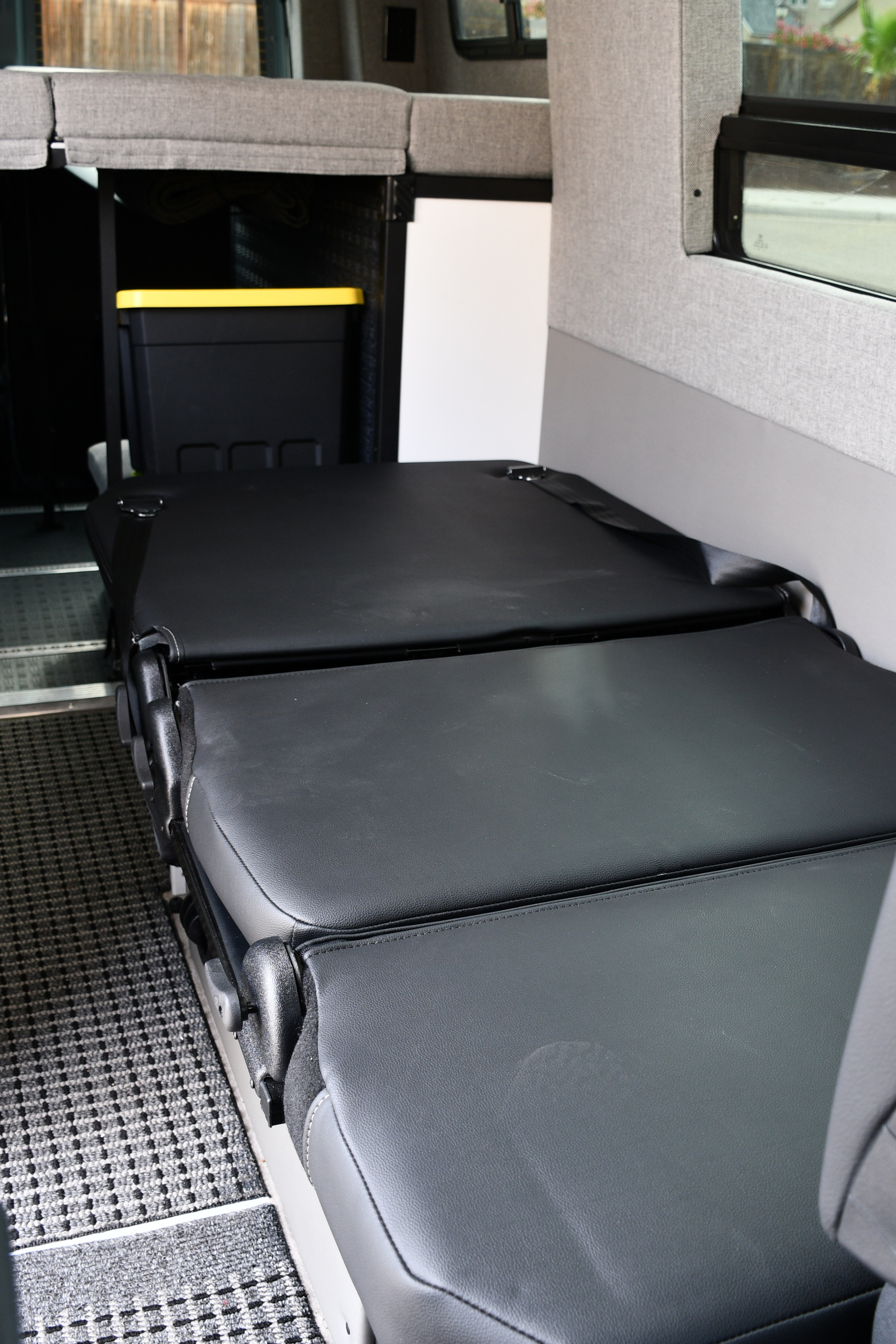 RV rental interior: modular black leather seats/bed, upper bunk, and storage. Ideal flexible living space.. Storyteller Overland Storyteller Overland Class B 2021