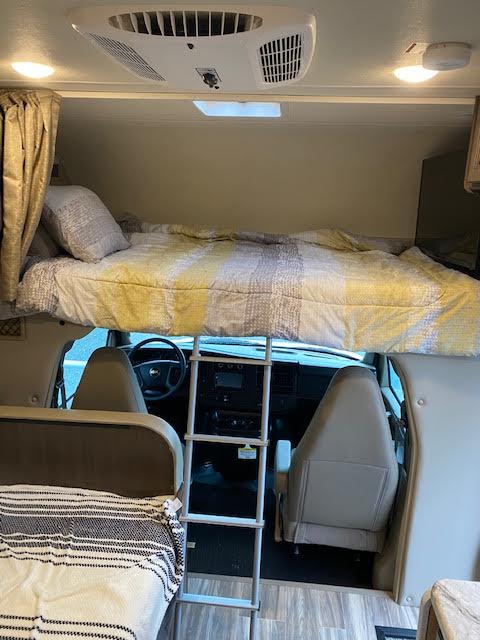 RV rental interior: cab-over bed with ladder, AC, and front cockpit. A comfortable camping space.. Thor Motor Coach Freedom Elite 2021