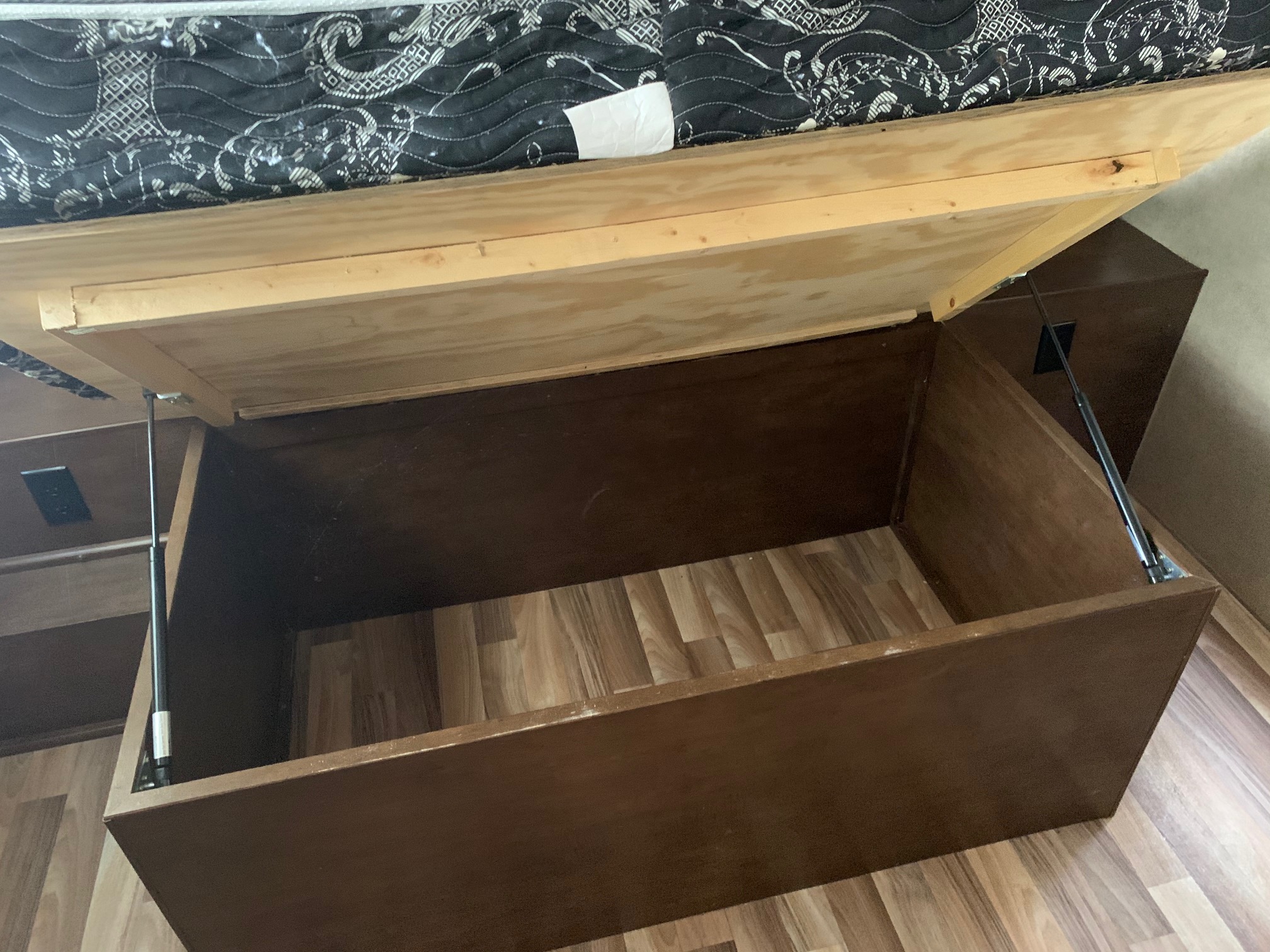 Efficient under-bed storage in an RV rental, showing a lift-up platform with gas struts and ample space.. Pacific Coachworks Other 2016