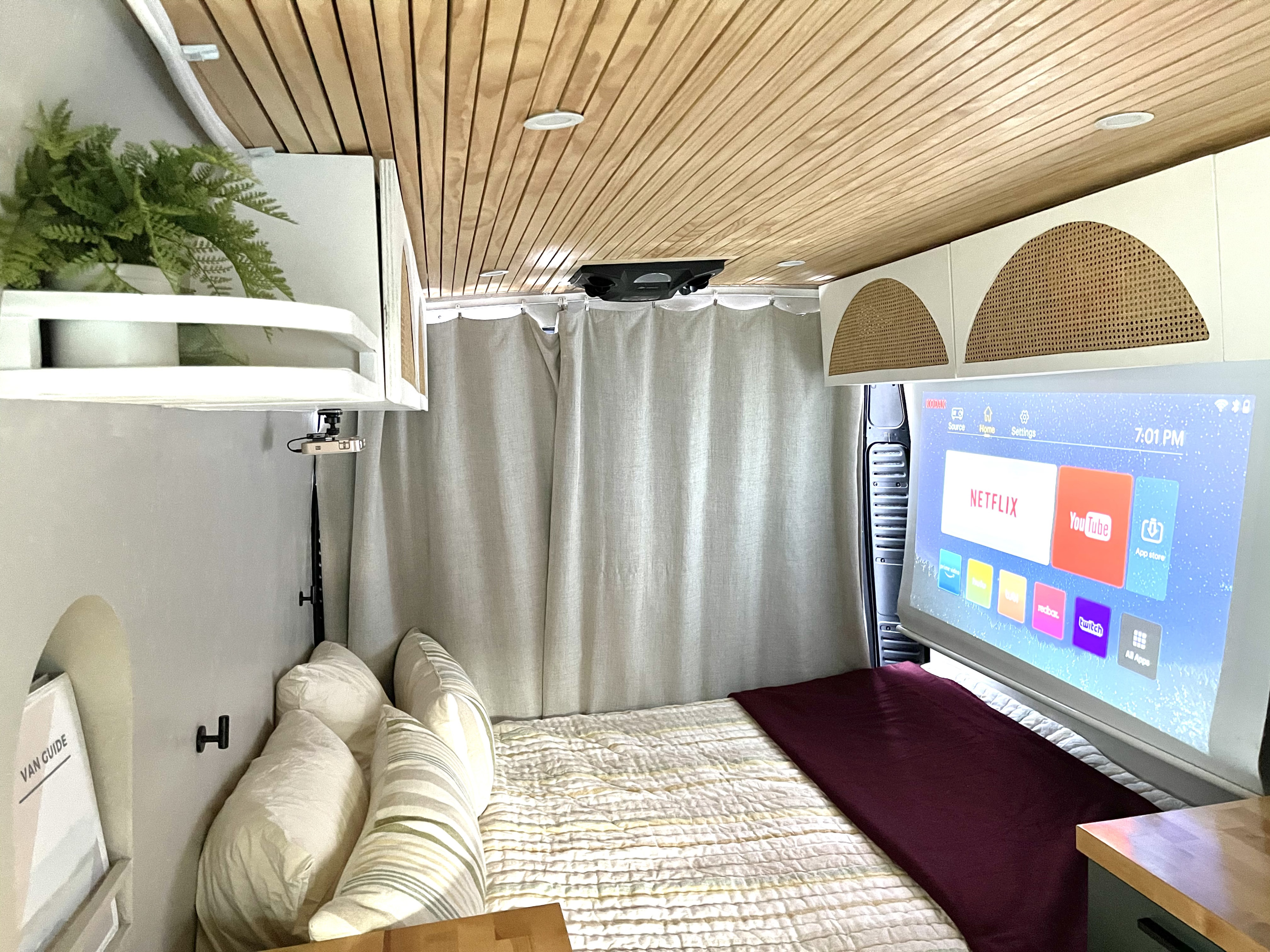 Inside a modern rv rental: a cozy sleeping area with a projector casting smart apps like Netflix & YouTube onto a screen.. Other Other 2015