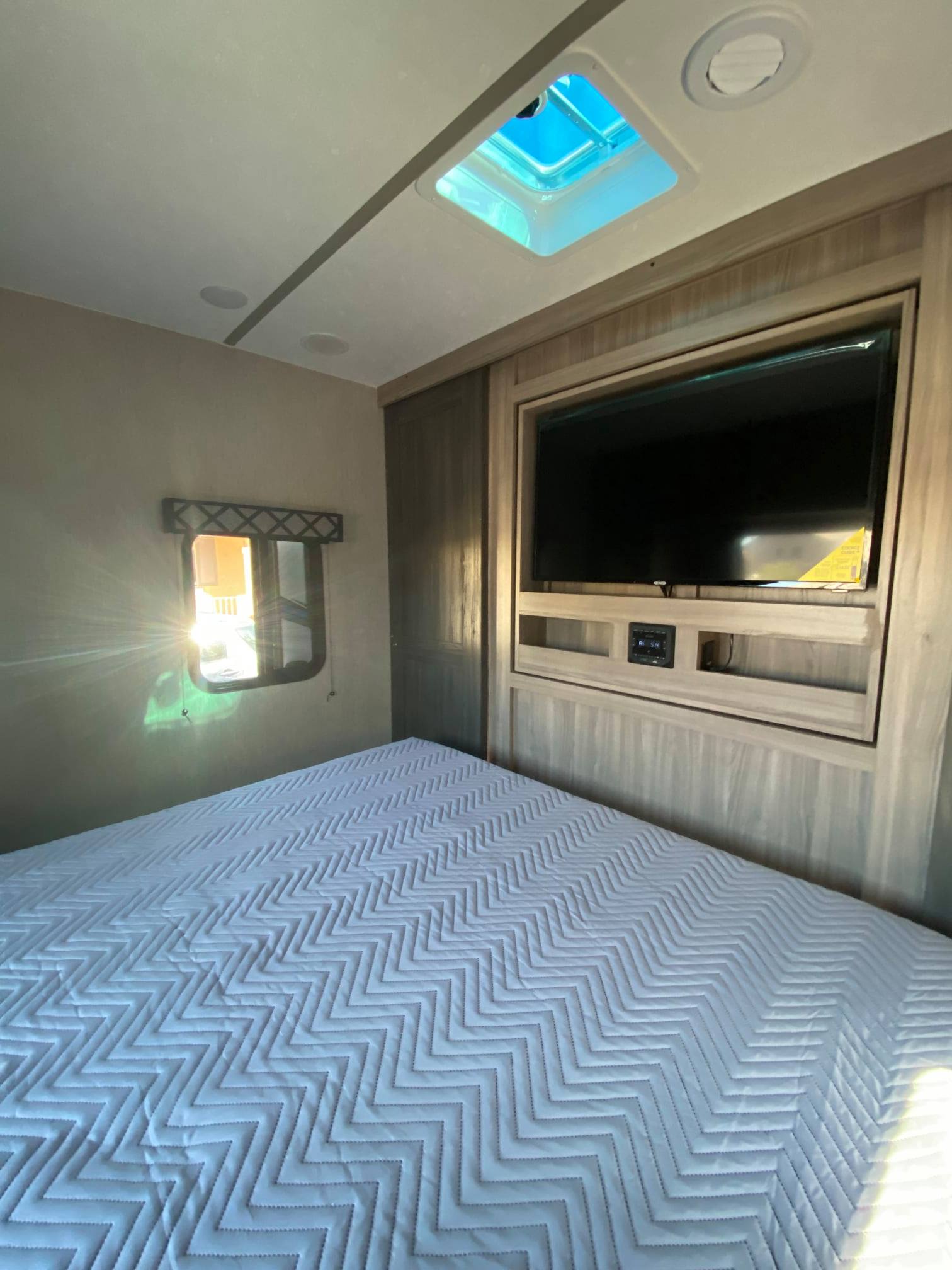 Cozy RV rental bedroom with TV, skylight, and a comfy bed. Ideal for travel trailer adventures.. Forest River Coachmen Freedom Express Ultra Lite 2021