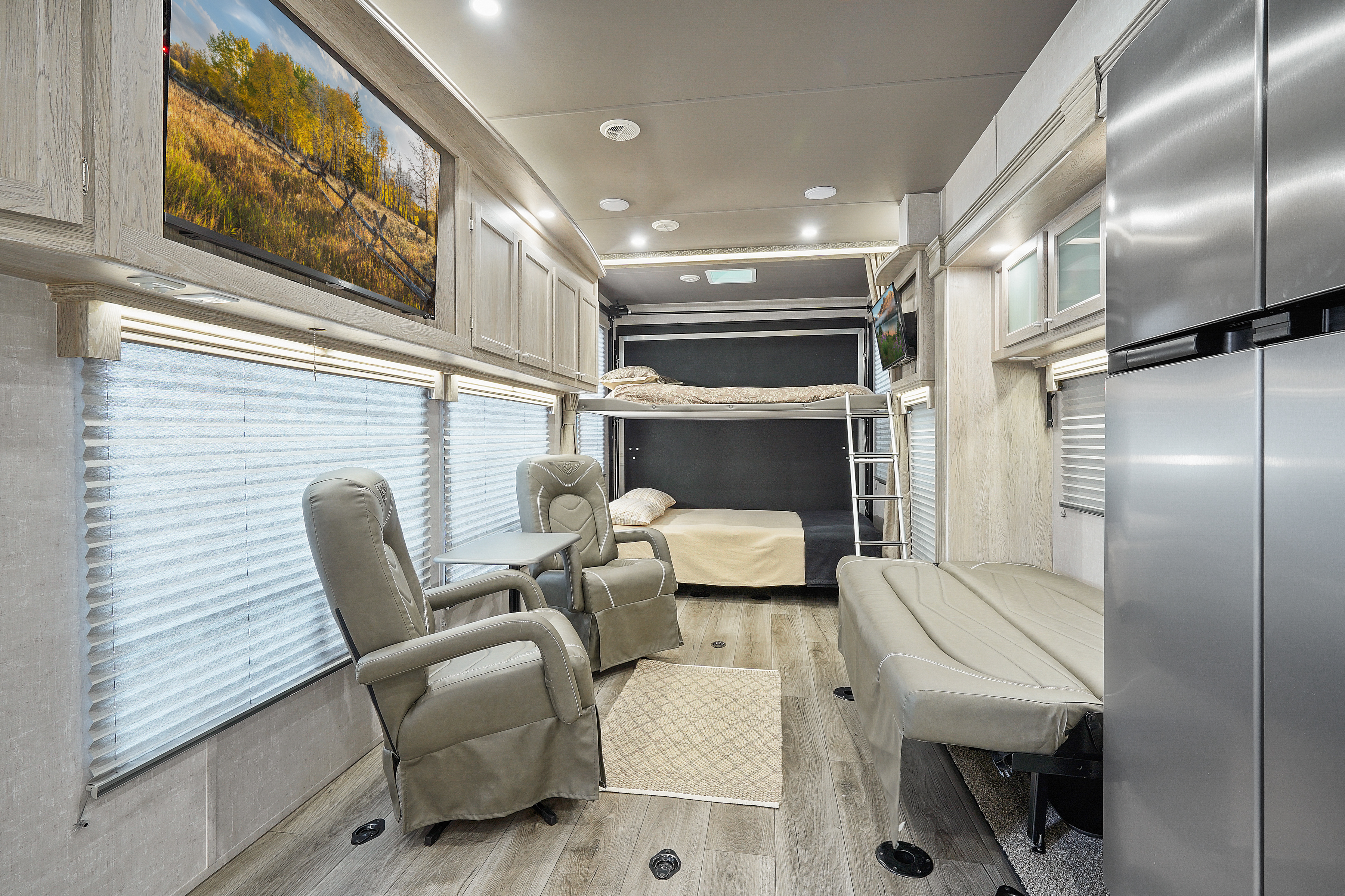 This RV rental interior features light wood cabinets, TV, cozy bunk beds, recliners, and a full-size fridge.. Eclipse Recreational Vehicles Attitude 2021