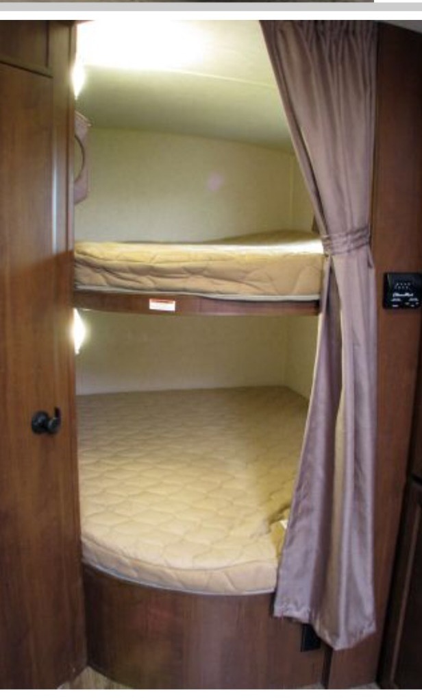 RV rental: cozy interior with two bunk beds, quilted mattresses, built-in lighting, and a tied-back privacy curtain.. Jayco White Hawk Ultra Lite 2015