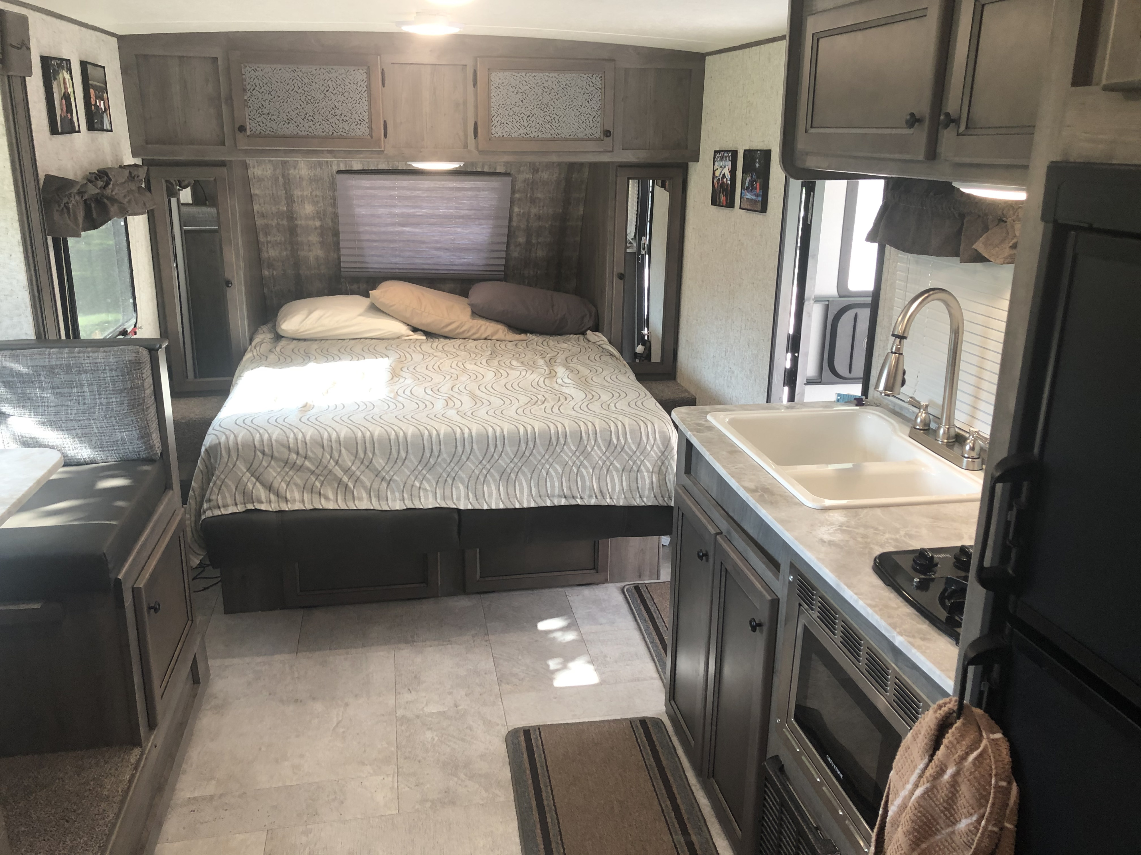 This RV rental interior offers a comfortable bedroom with a queen bed, kitchen, and dinette for travelers.. Coachmen Apex 2019