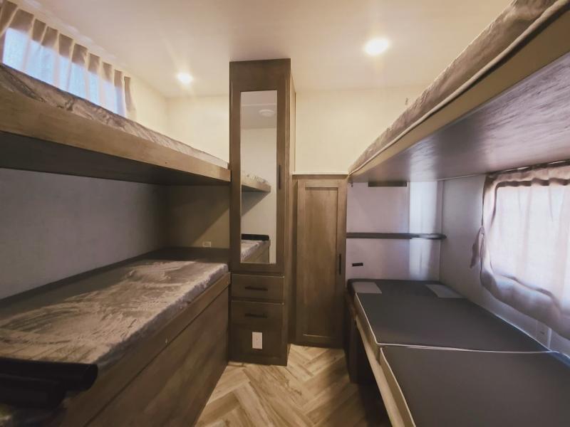 Spacious RV rental interior featuring two sets of comfortable bunk beds, ample storage, and a mirror. Ready for your adventure.. Forest River Wildwood 2021