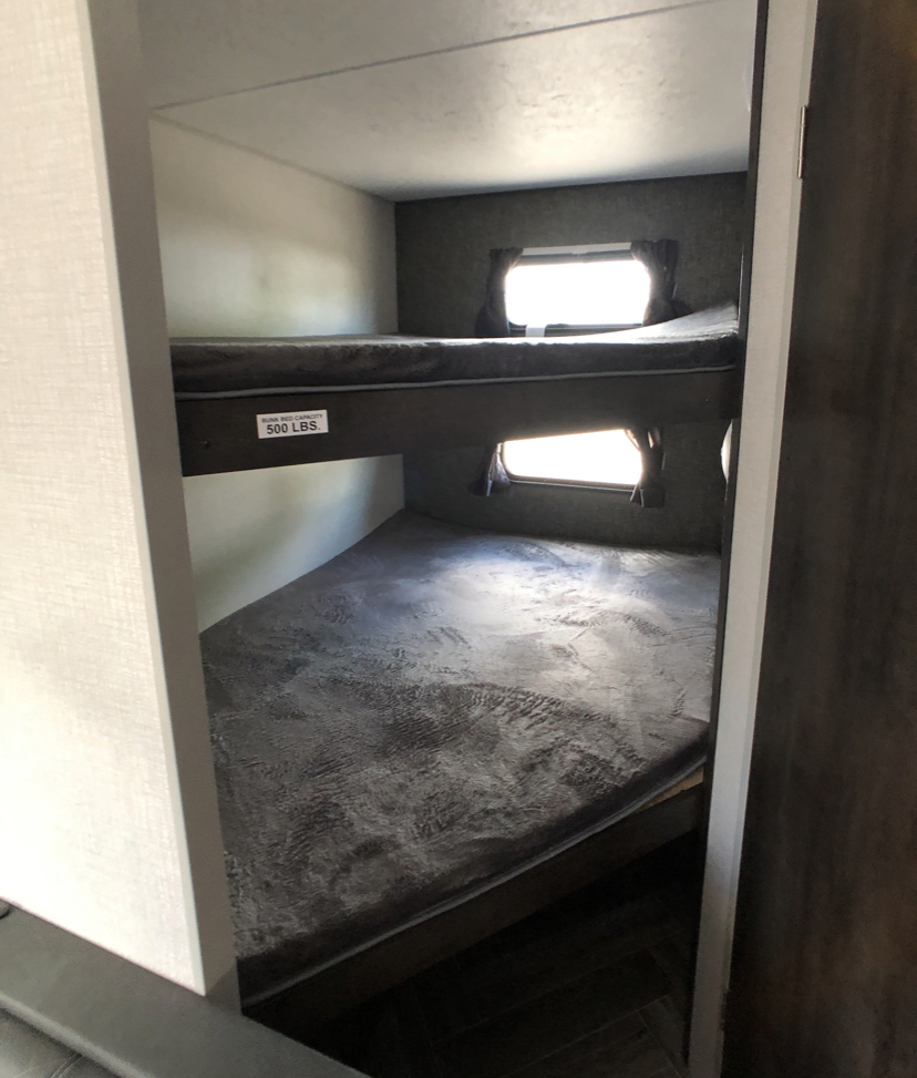 Cozy bunk beds in an RV rental, offering compact sleeping arrangements. Top bunk capacity: 500 lbs.. K-Z Manufacturing Sportsmen 2019