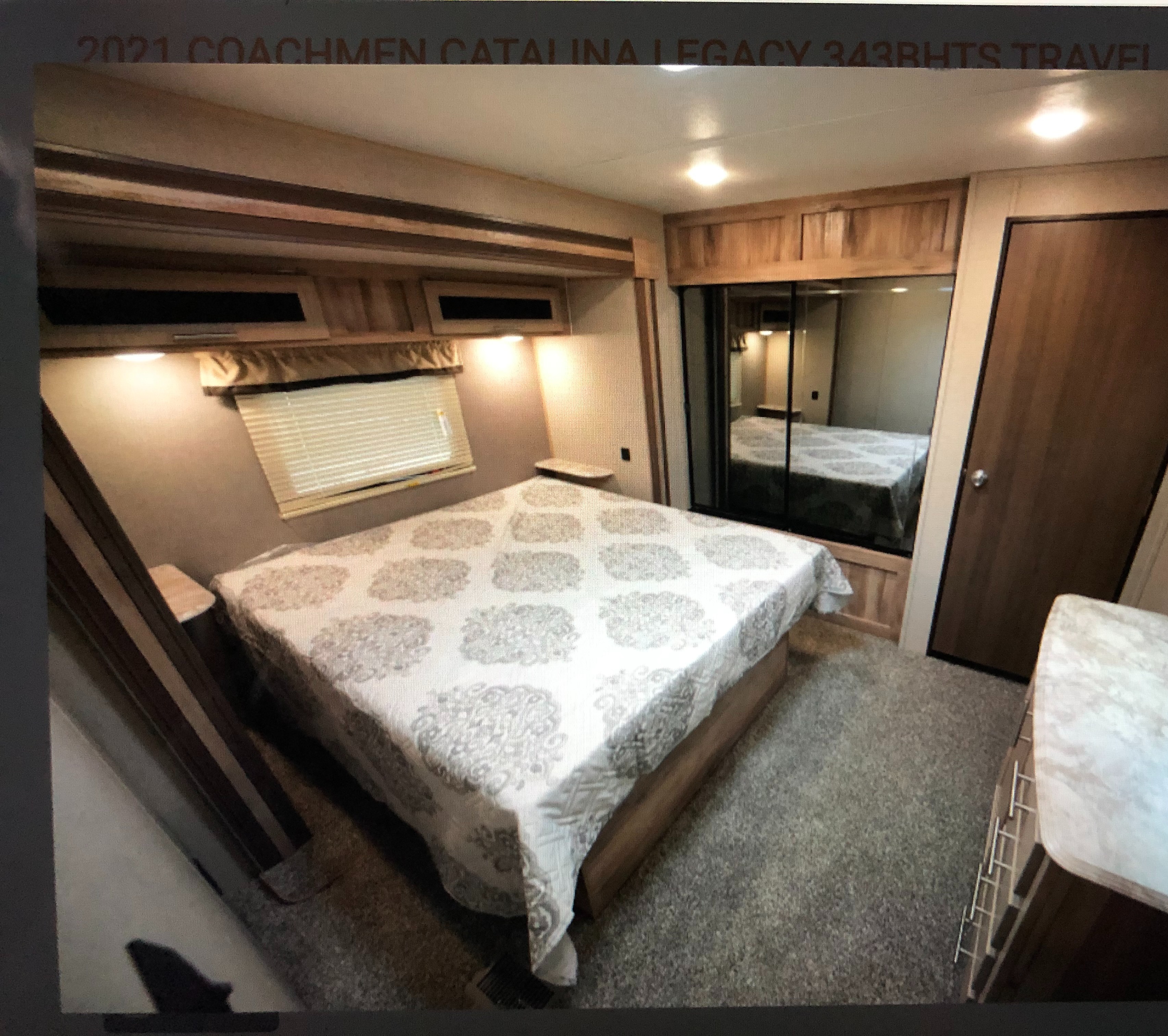 Well-appointed travel trailer bedroom featuring a comfortable bed, mirrored closet, and dresser, ideal for your rv rental.. Coachmen Catalina 2021