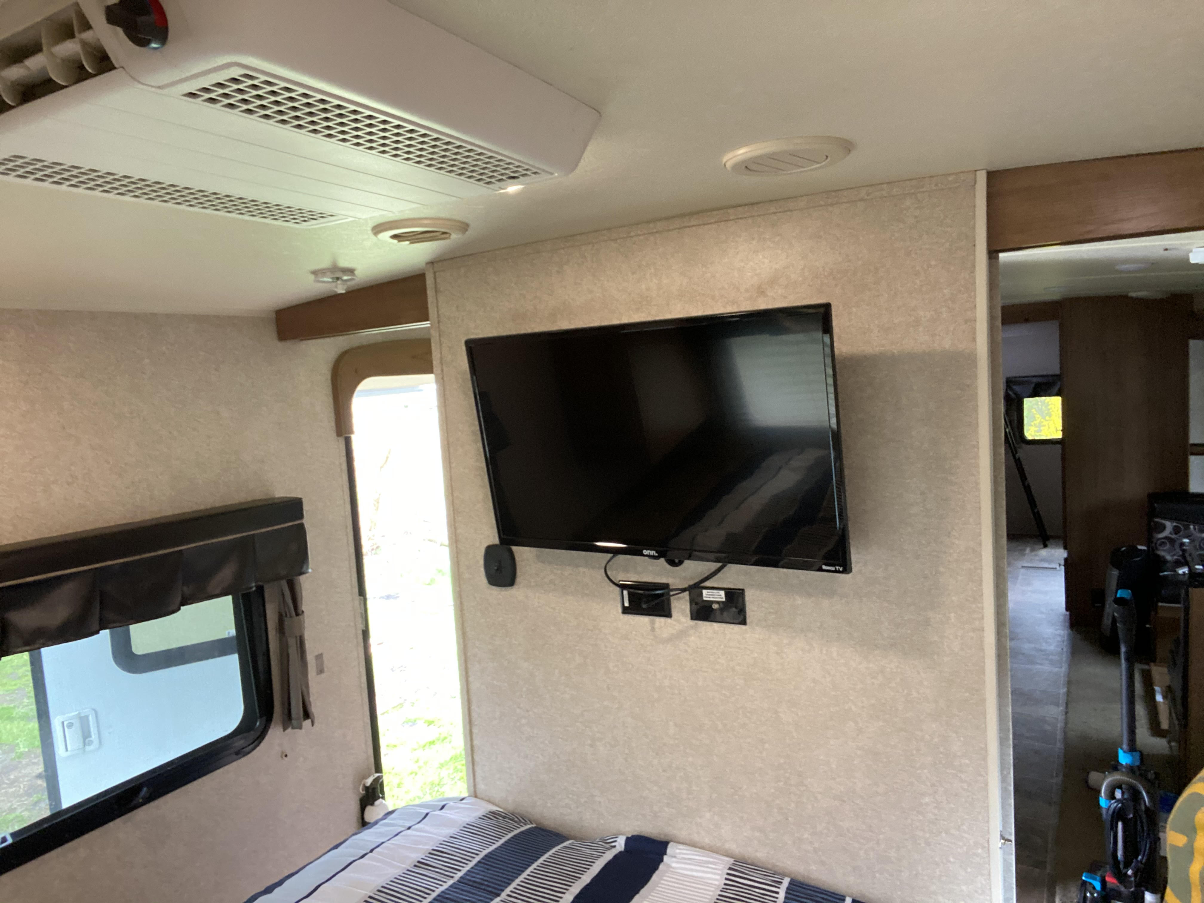 RV rental interior: A cozy bedroom with overhead AC, wall-mounted TV, and window view. Ideal for mobile living.. Forest River Rockwood Signature Ultra 2016