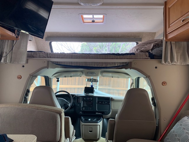 RV rental interior view: bunk bed above cab, driver's area, and living space with TV on left.. Thor Chateau 2008