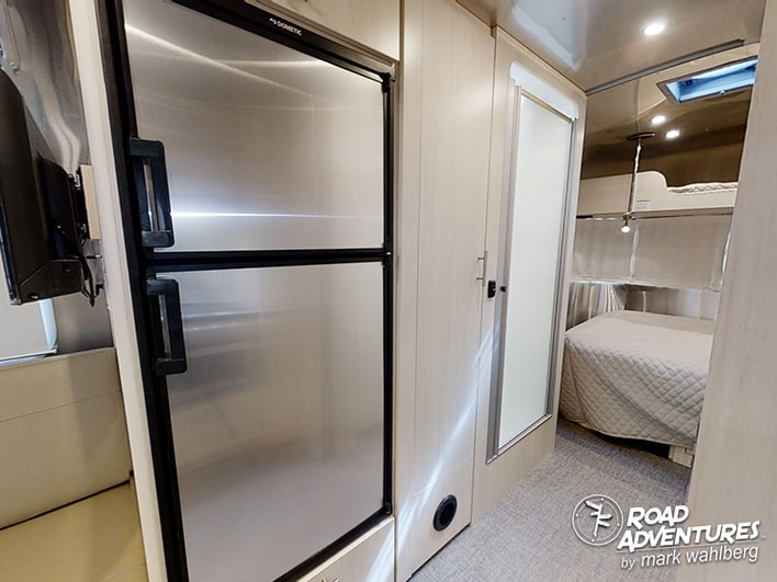 RV rental's compact living space: fridge, TV, bath, and a cozy bedroom with bunk beds. Perfect for travel.. Airstream Flying Cloud 25FB Queen 2021