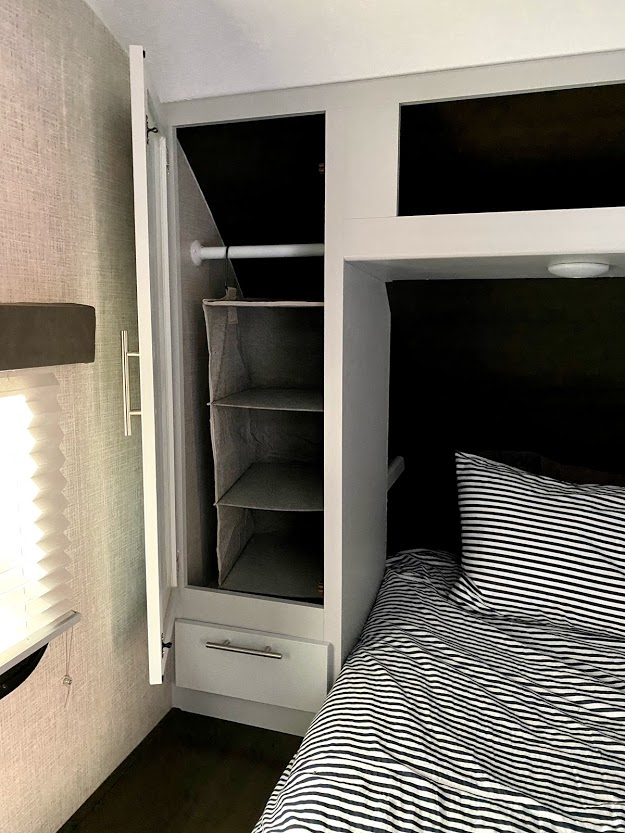 Optimized RV rental space: a compact bedroom features a hanging closet organizer and striped bunk bed.. Keystone Bullet 2021