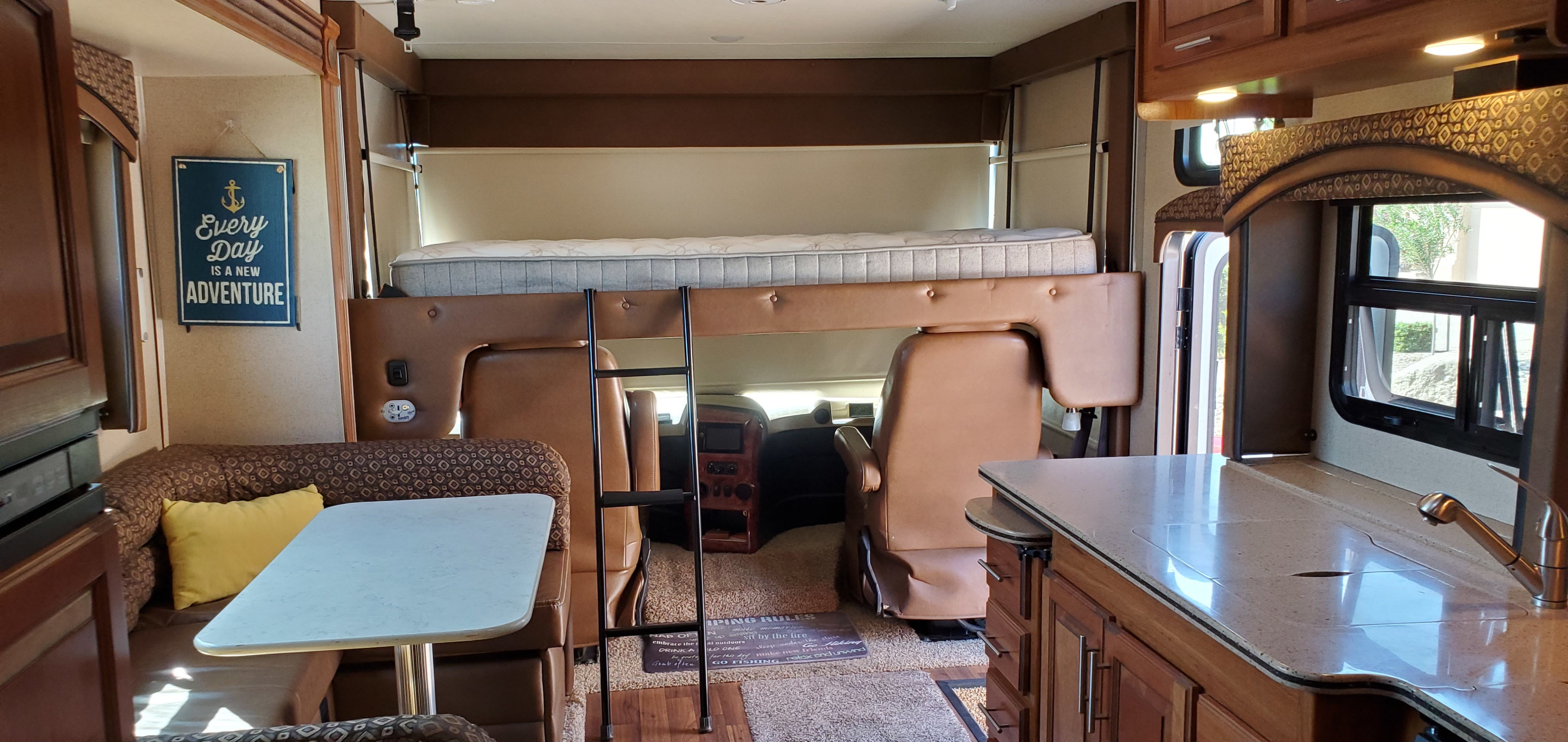 Inside a cozy RV rental: an overhead bunk, dinette with table, and kitchen counter for your next adventure.. Jayco Precept 2016