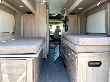 RV rental interior: A central aisle divides two beds with storage beneath, leading to the driver's cab. Ideal for camper adventures.. Thor Sequence 2021