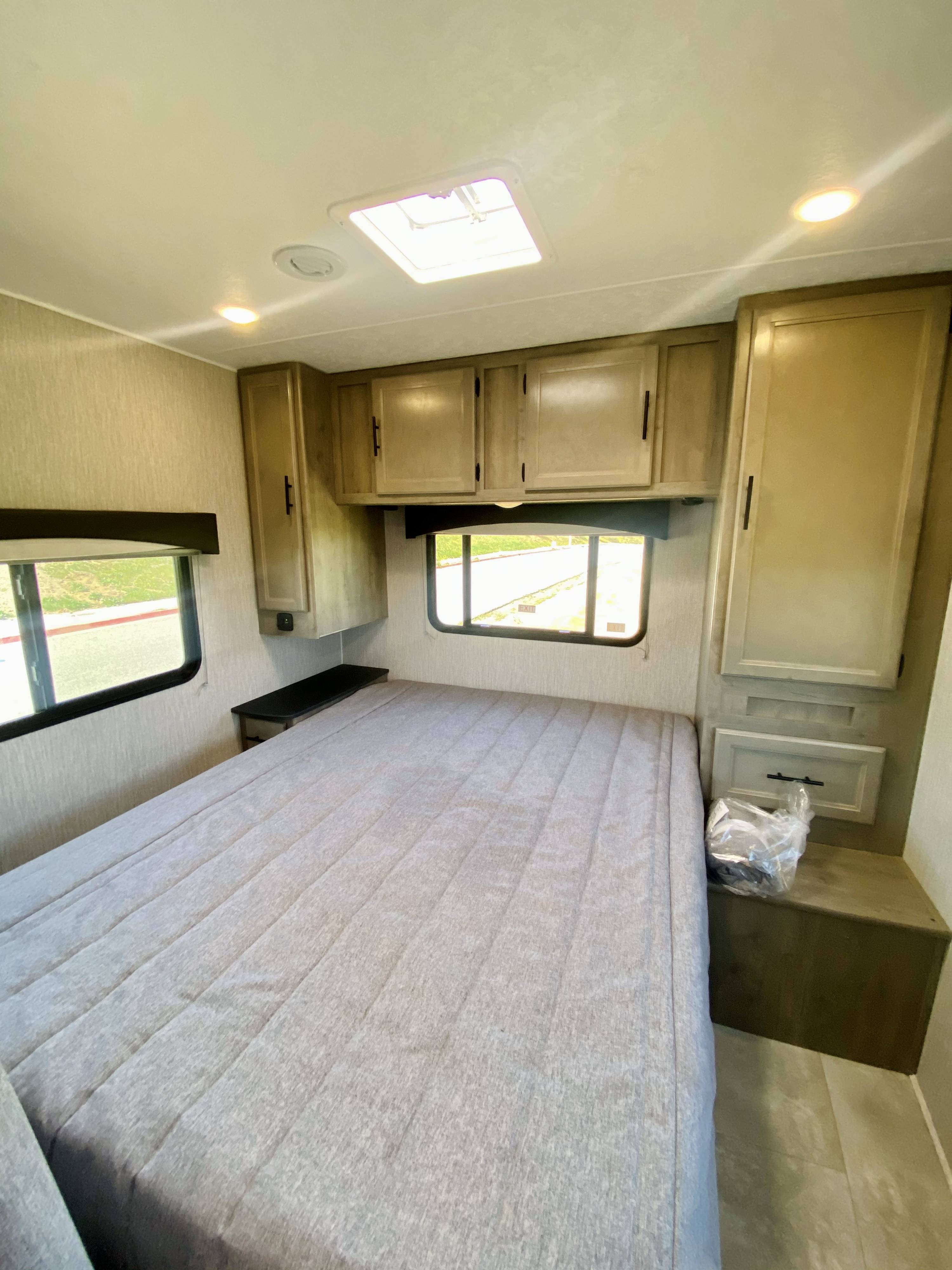Modern RV rental bedroom featuring a large bed, overhead cabinets, and bright windows. Perfect for your next adventure.. Coachmen Freelander 2021
