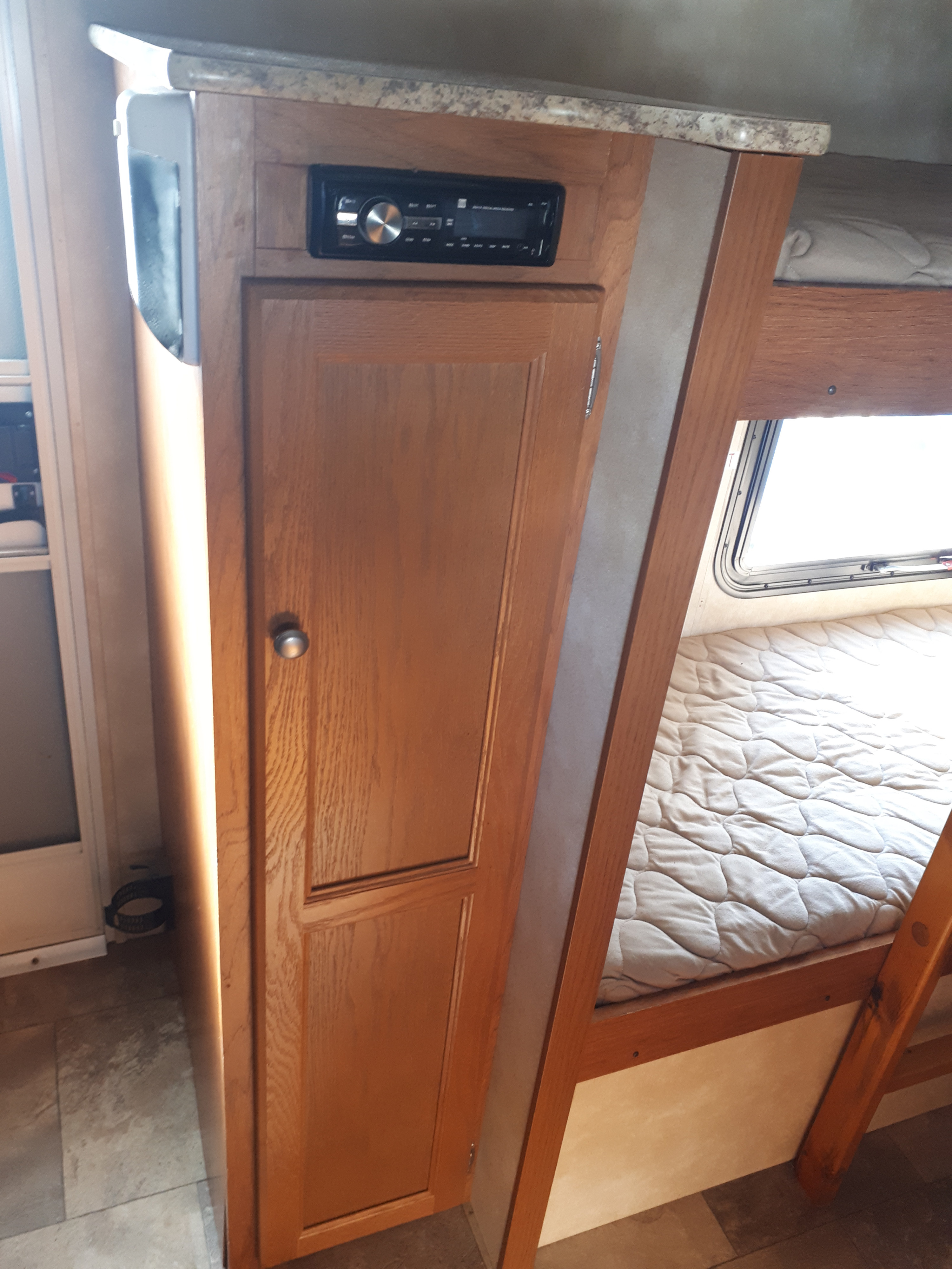 RV rental: Interior showing wooden cabinet, integrated stereo, and bunk beds with window and quilted mattress.. Coachmen Clipper 2013