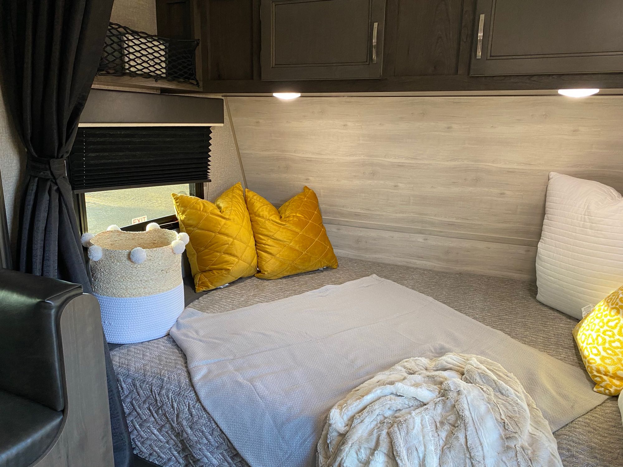 Step inside this cozy RV rental bedroom. It features a neatly made bed with yellow & white pillows, blankets, and storage.. Jayco Jay Flight Swift 2021