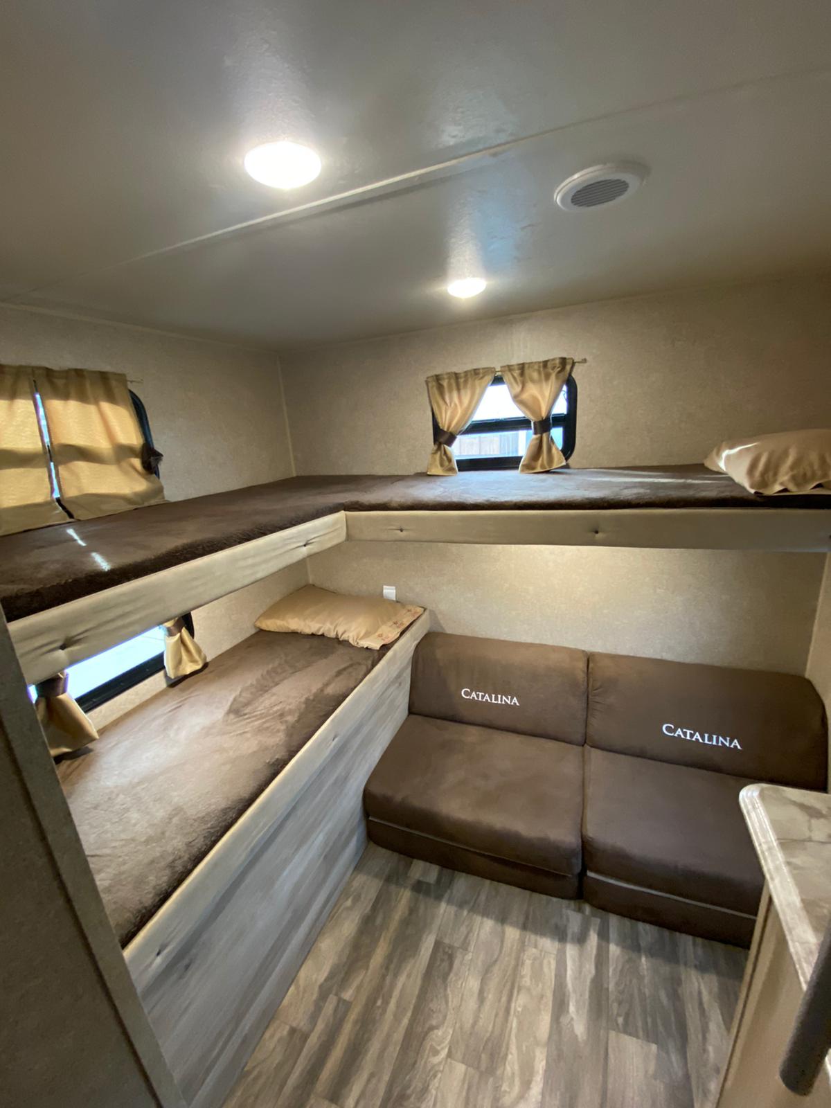 RV rental interior with a bunkhouse layout featuring two bunk beds and a comfortable sofa. Ideal for families.. Coachmen Catalina 2019