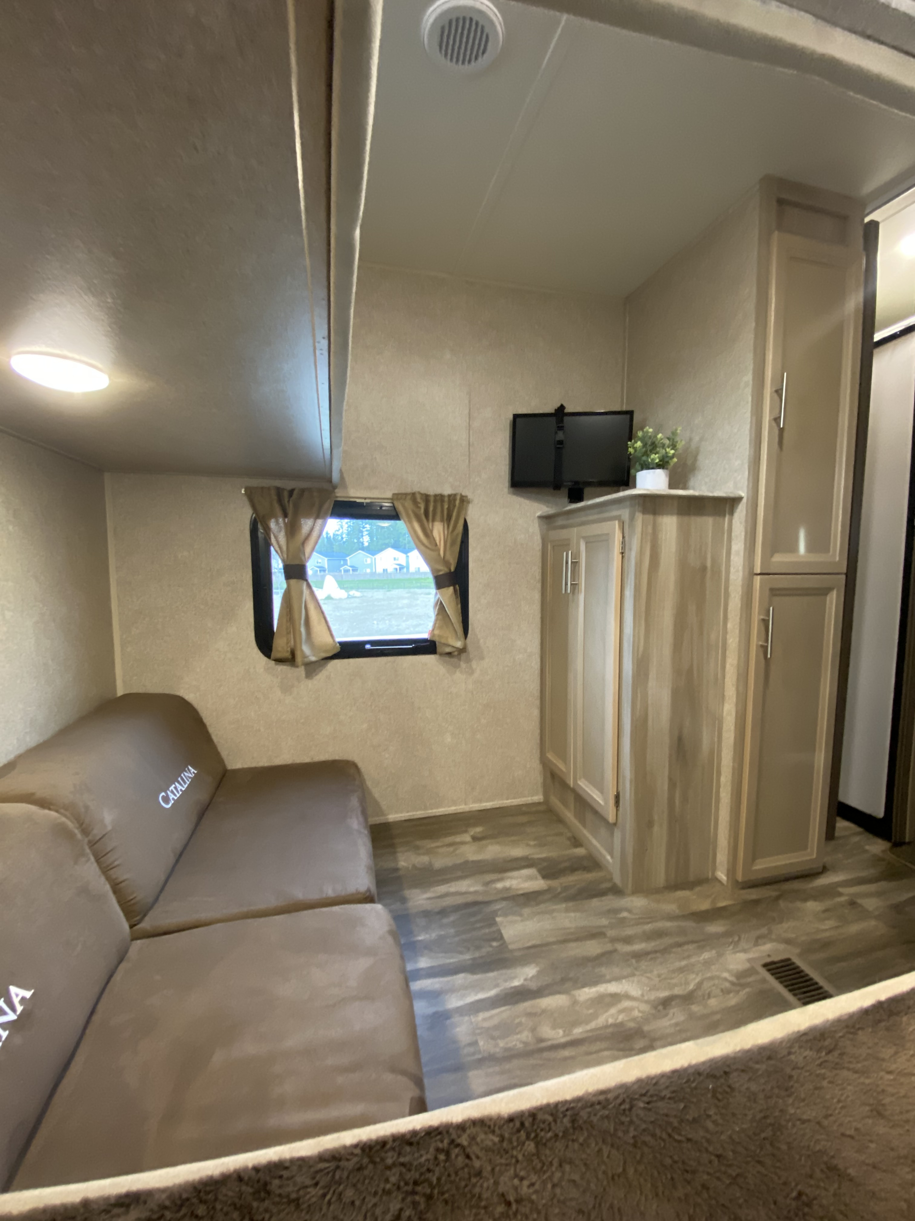 Step inside this cozy RV rental, featuring a comfortable brown couch, wall-mounted TV, and ample storage for your journey.. Coachmen Catalina 2019