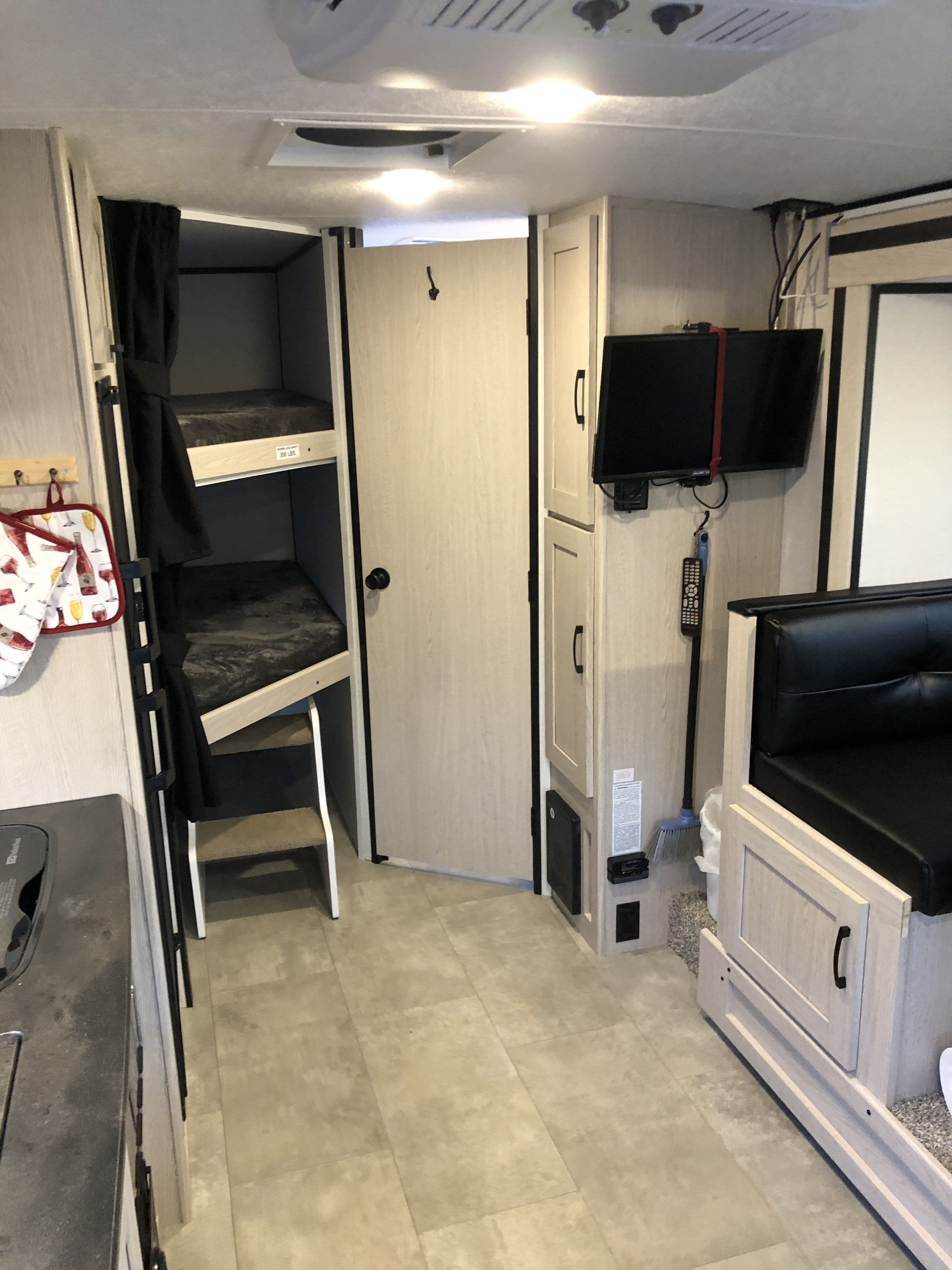 RV rental interior features bunk beds, a dinette booth, kitchen counter, TV, and storage cabinets, ready for your trip.. Coachmen Apex 2021