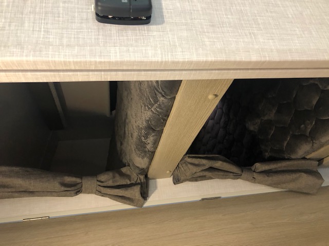 RV rental interior: Under-counter storage with two cubbies. The right cubby holds a dark cushion, fabric ties secure items.. Forest River Rockwood Geo Pro 2021