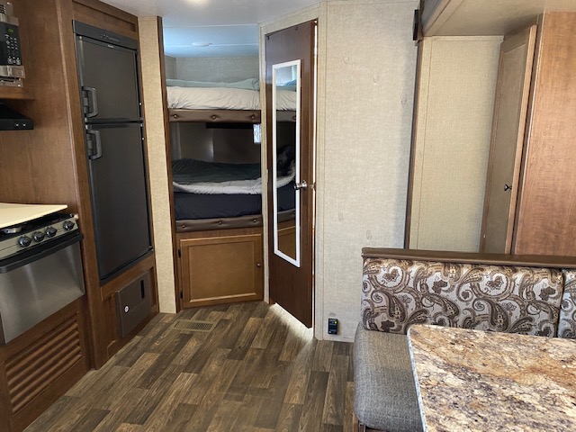 RV rental interior: well-equipped kitchen, two bunk beds, and a dining nook with patterned cushions. Ready for travel.. Keystone Hideout 2017