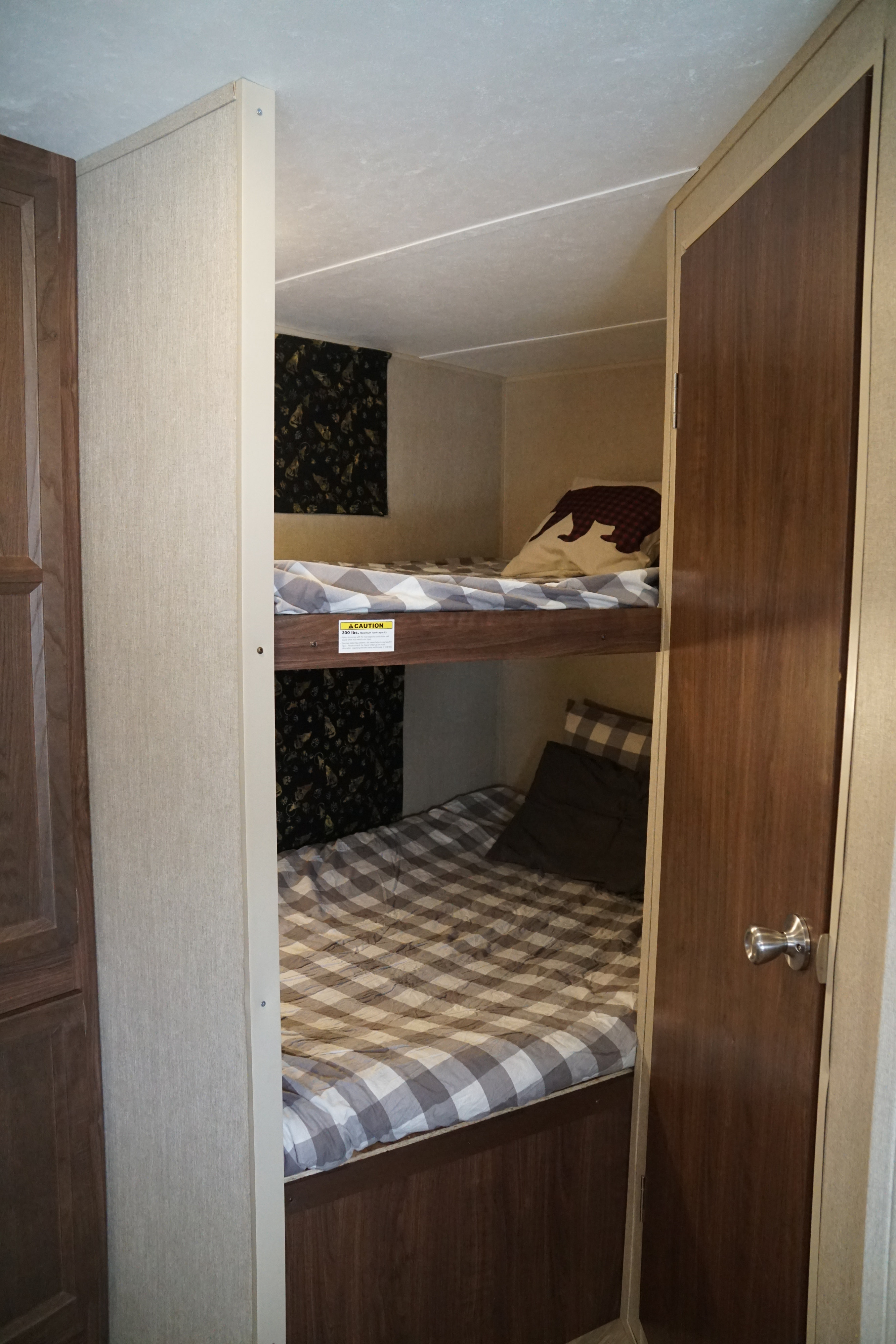 Inside a cozy rv rental, featuring bunk beds ready for occupants. The top bunk has a 300 lbs weight capacity sticker.. Coleman Lantern Edition 262 BH 2017