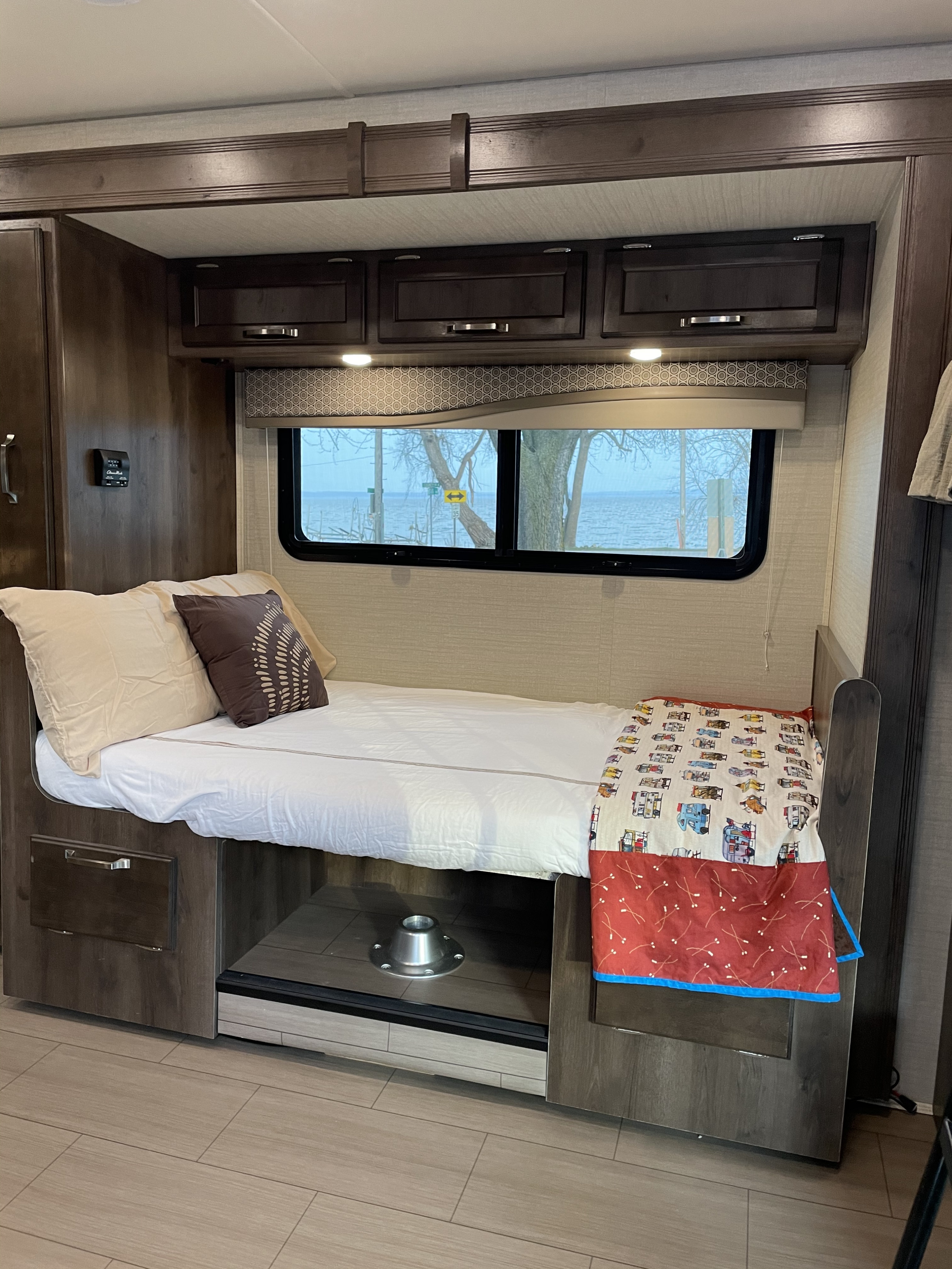 Cozy RV rental interior with a comfortable bed, smart storage solutions, and a picturesque window view.. Jayco Melbourne 2018