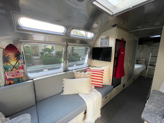 Cozy Airstream RV rental interior with a bright living area, gray sofa, TV, and bunk beds visible at the rear.. Airstream Flying Cloud 2021