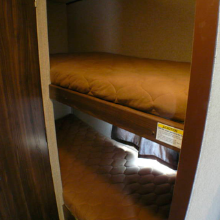 RV rental bunk beds: Two stacked beds with brown quilted mattresses offer cozy sleeping space inside a recreational vehicle.. Coachmen nano 2017