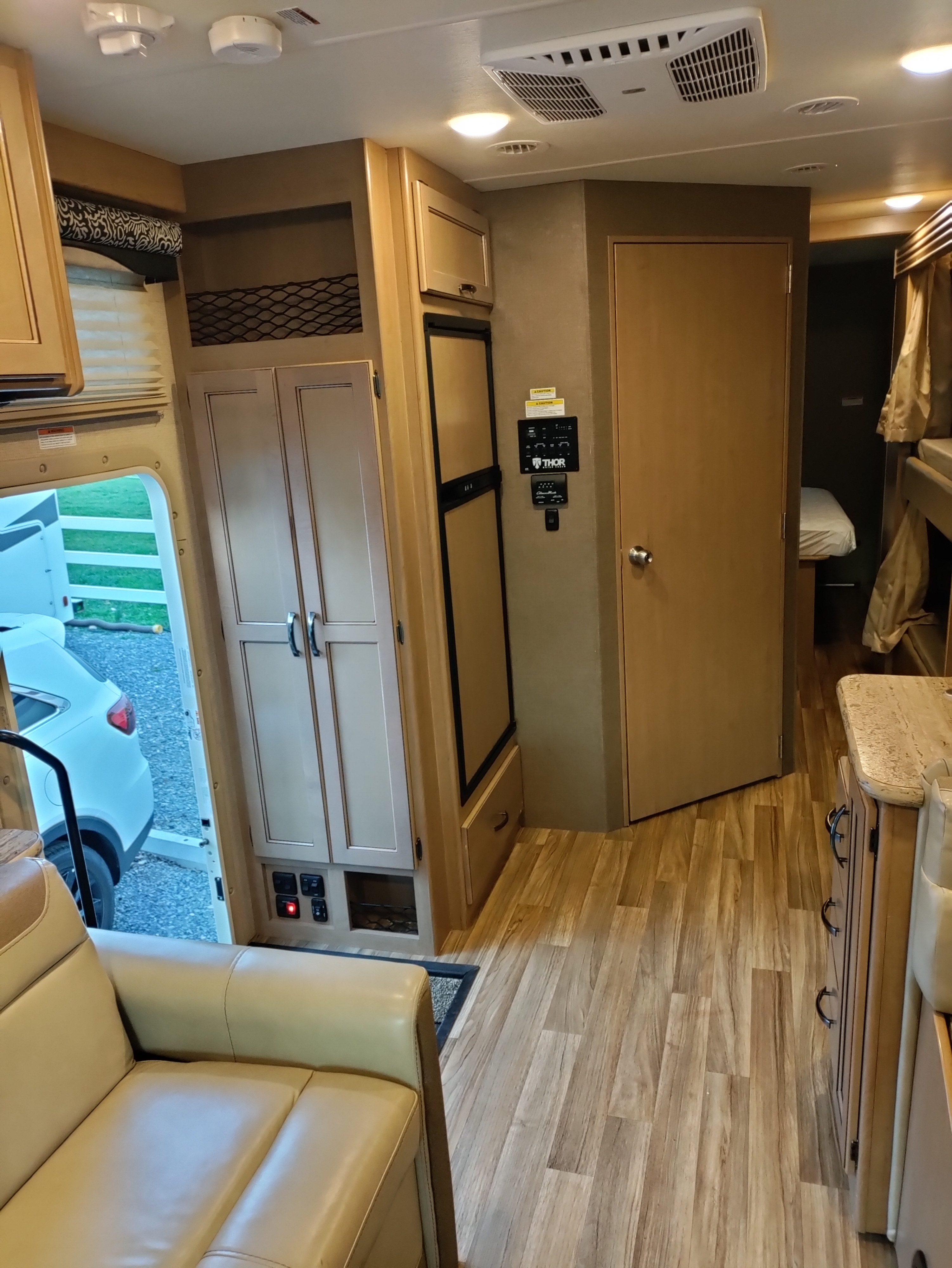 Inside a comfy RV rental: view of living area, kitchen, storage, and bunk beds, showing diverse amenities.. Thor Motor Coach A.C.E 2018