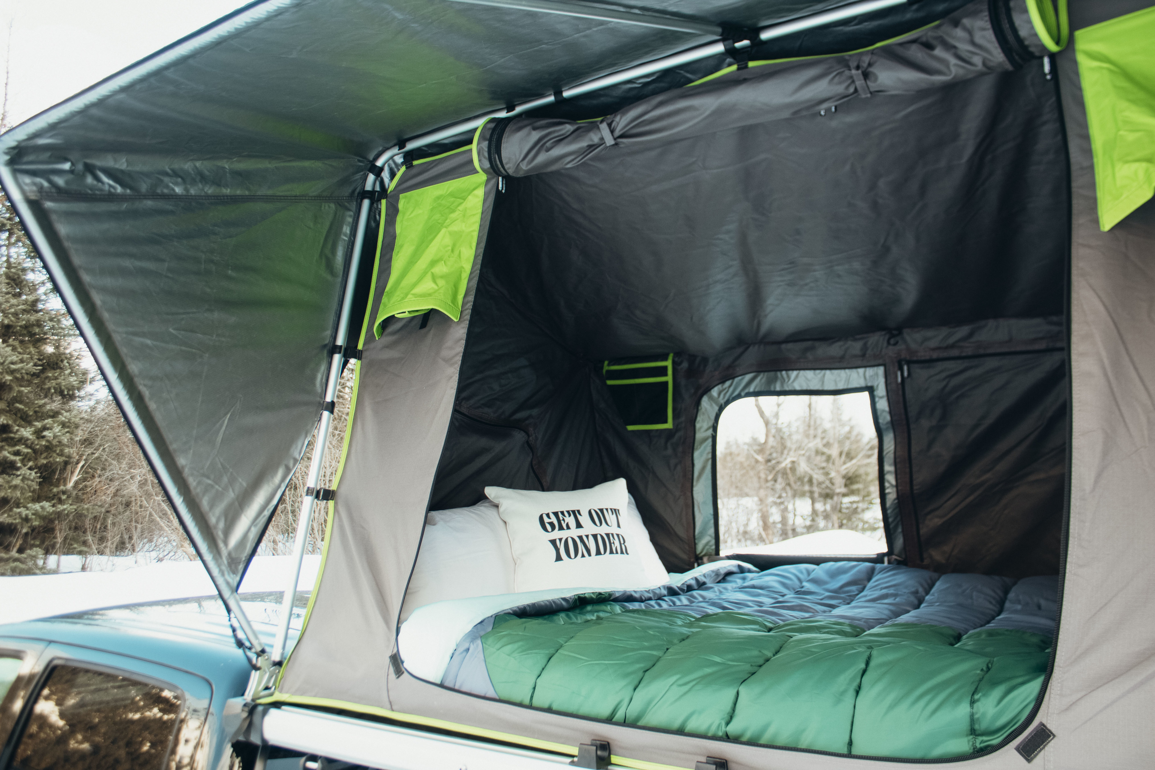 Inside a comfy rooftop tent from an RV rental, ideal for winter camping in nature with a cozy bed.. Toyota Tacoma 2021