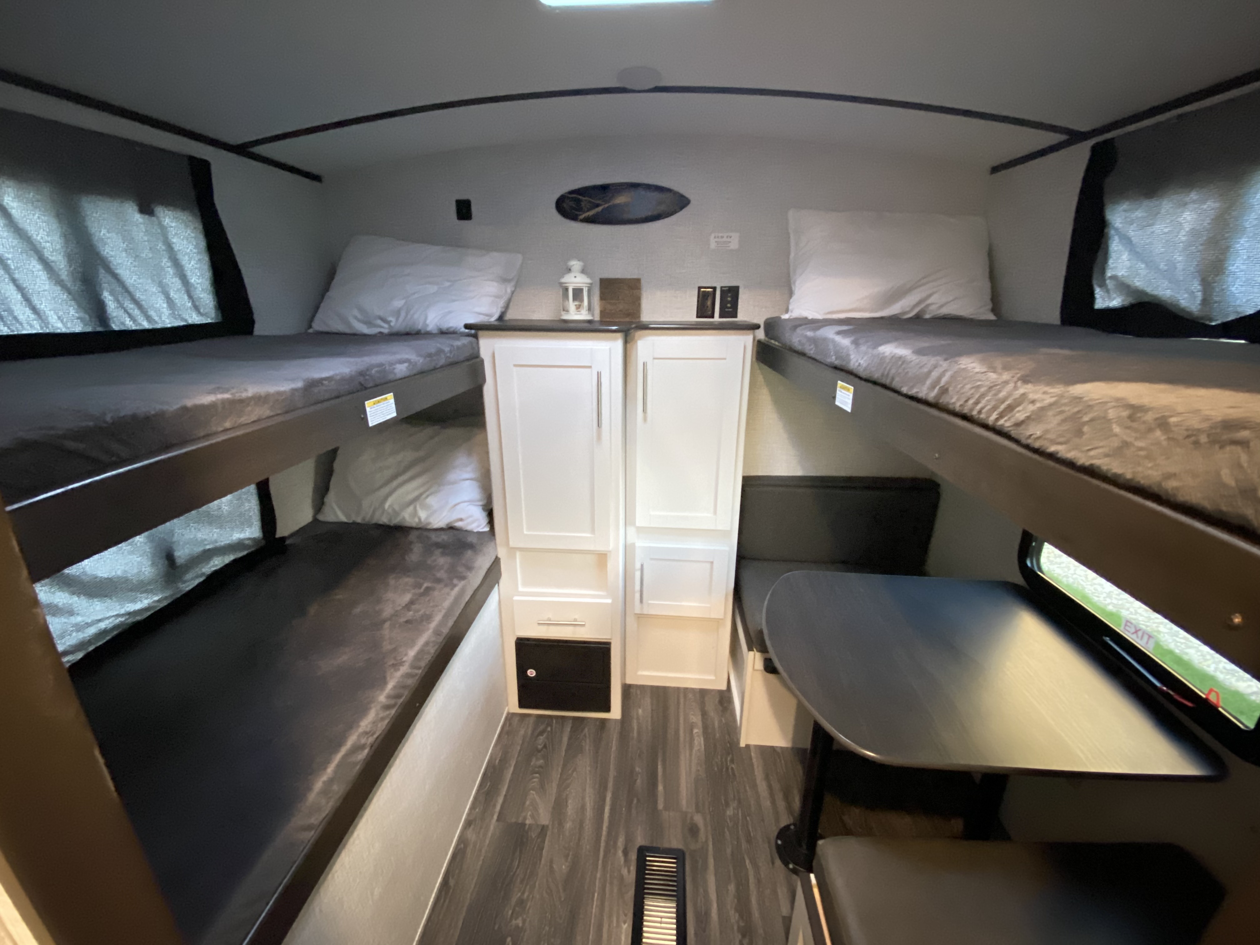 An RV rental bunkhouse: multiple bunk beds, a central cabinet unit, and a dinette table with seating.. Keystone RV Bullet Ultra Lite 2021