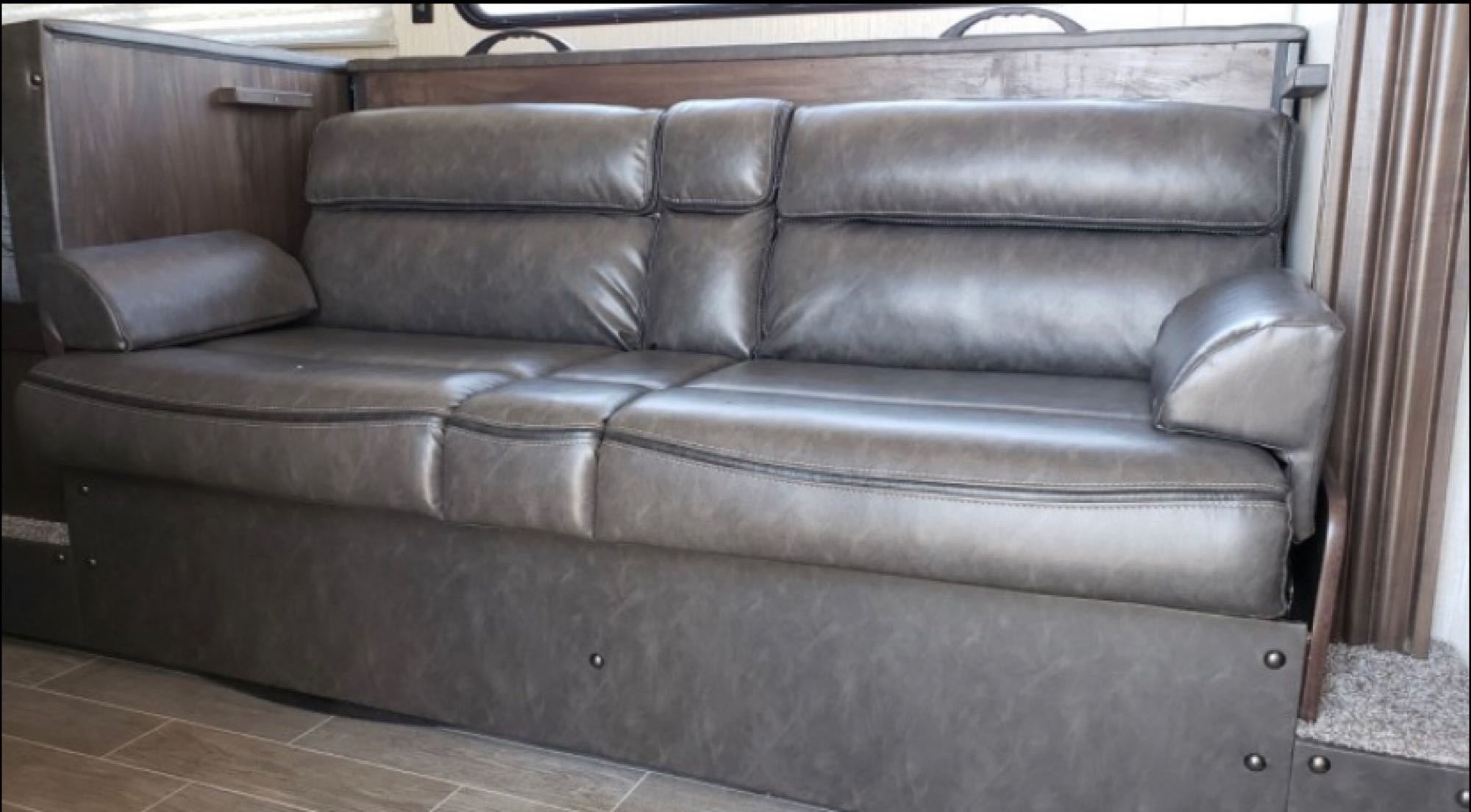 Modern gray leather sofa inside an RV rental, offering versatile seating or a bed for guests.. Forest River Cherokee Wolf Pup 2020