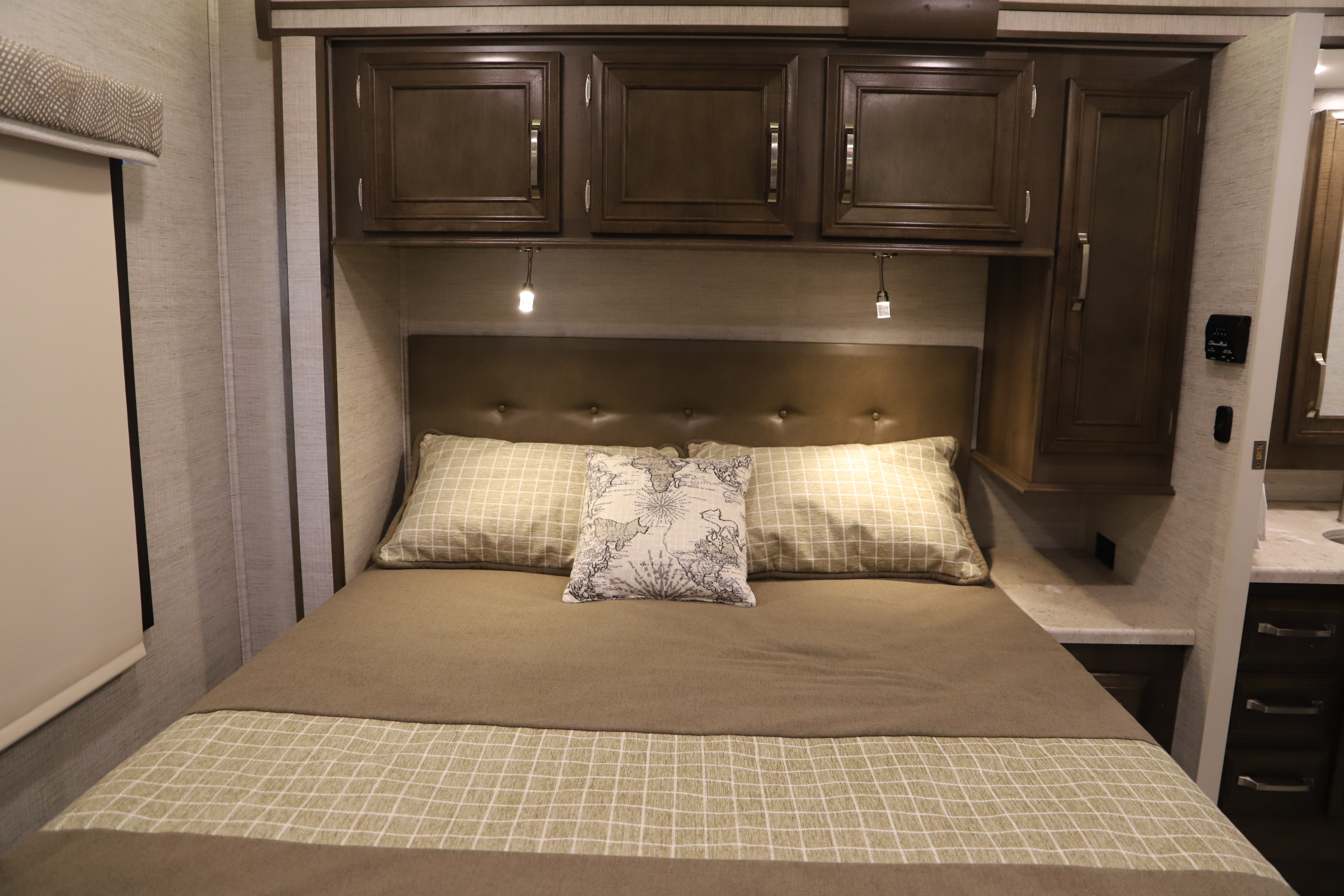 RV rental bedroom featuring a cozy bed, ample overhead cabinets, and reading lights. Compact and functional design.. Entegra Entergra Coach Steam 30X 2021