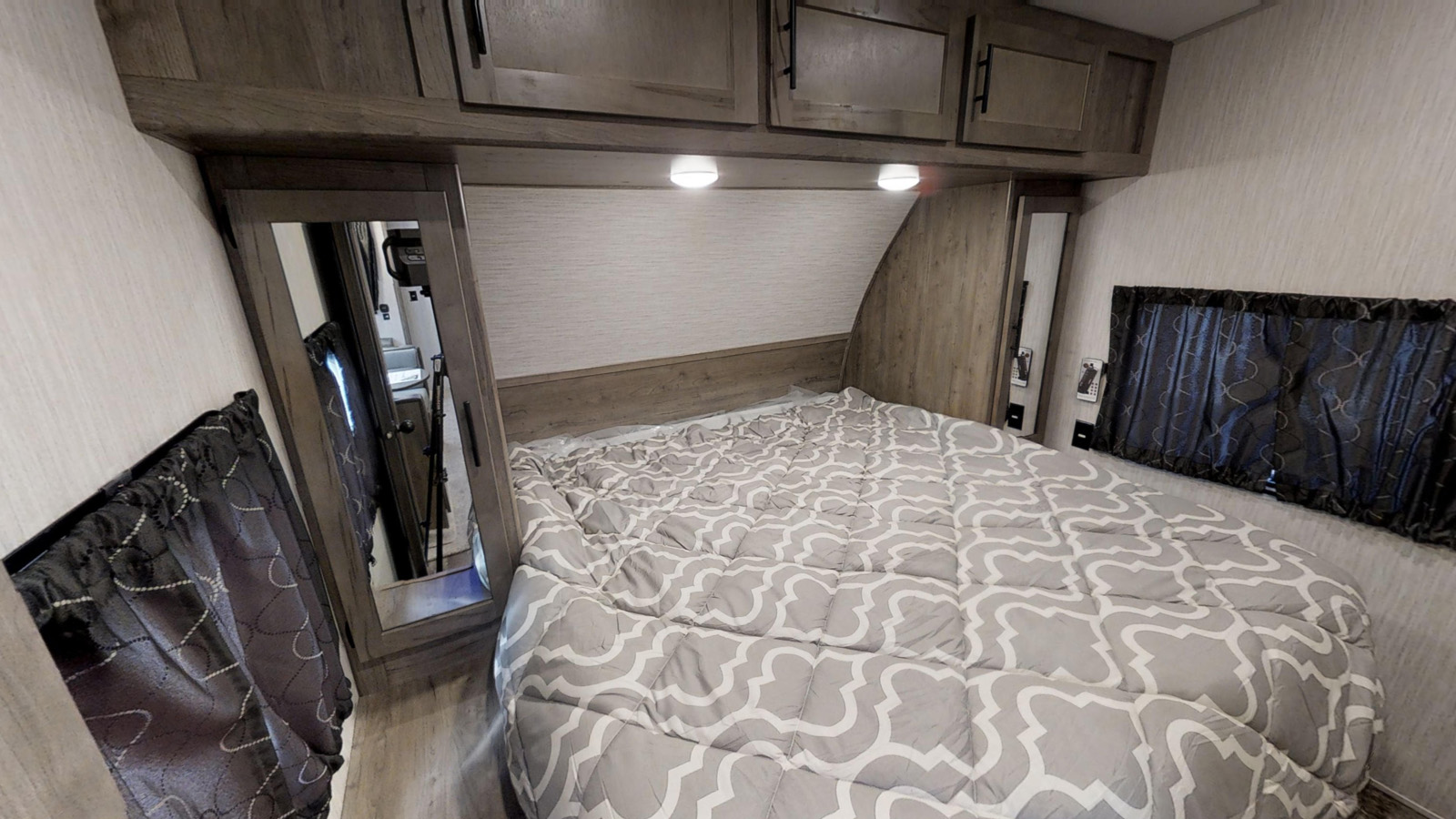 RV rental bedroom featuring a full-size bed, mirrored closet, and overhead storage.. Forest River Cherokee Wolf Pack 2021