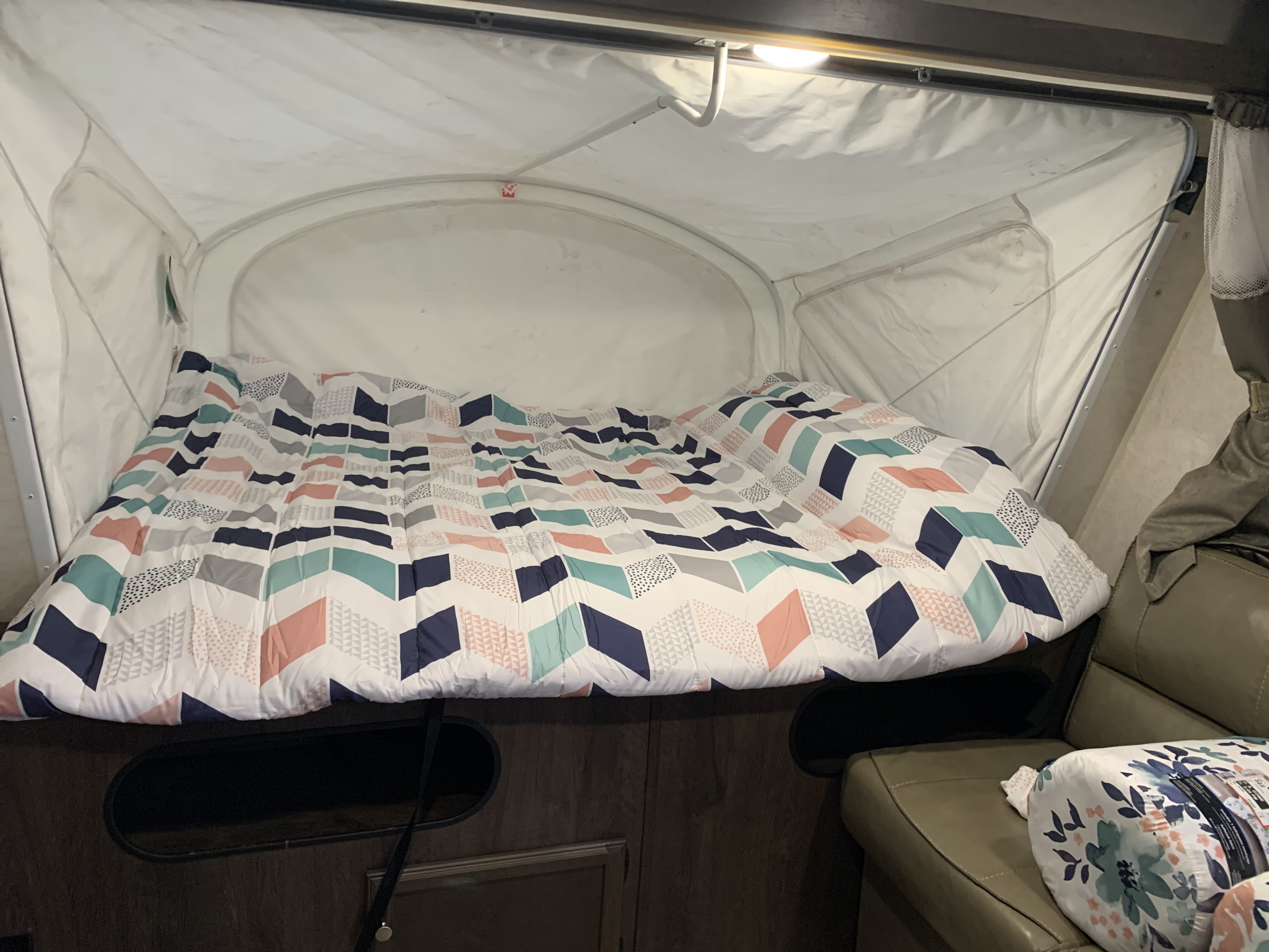 RV rental pop-up camper interior, showing a bright bed with a geometric comforter and cozy sleeping space.. Starcraft Launch 2018