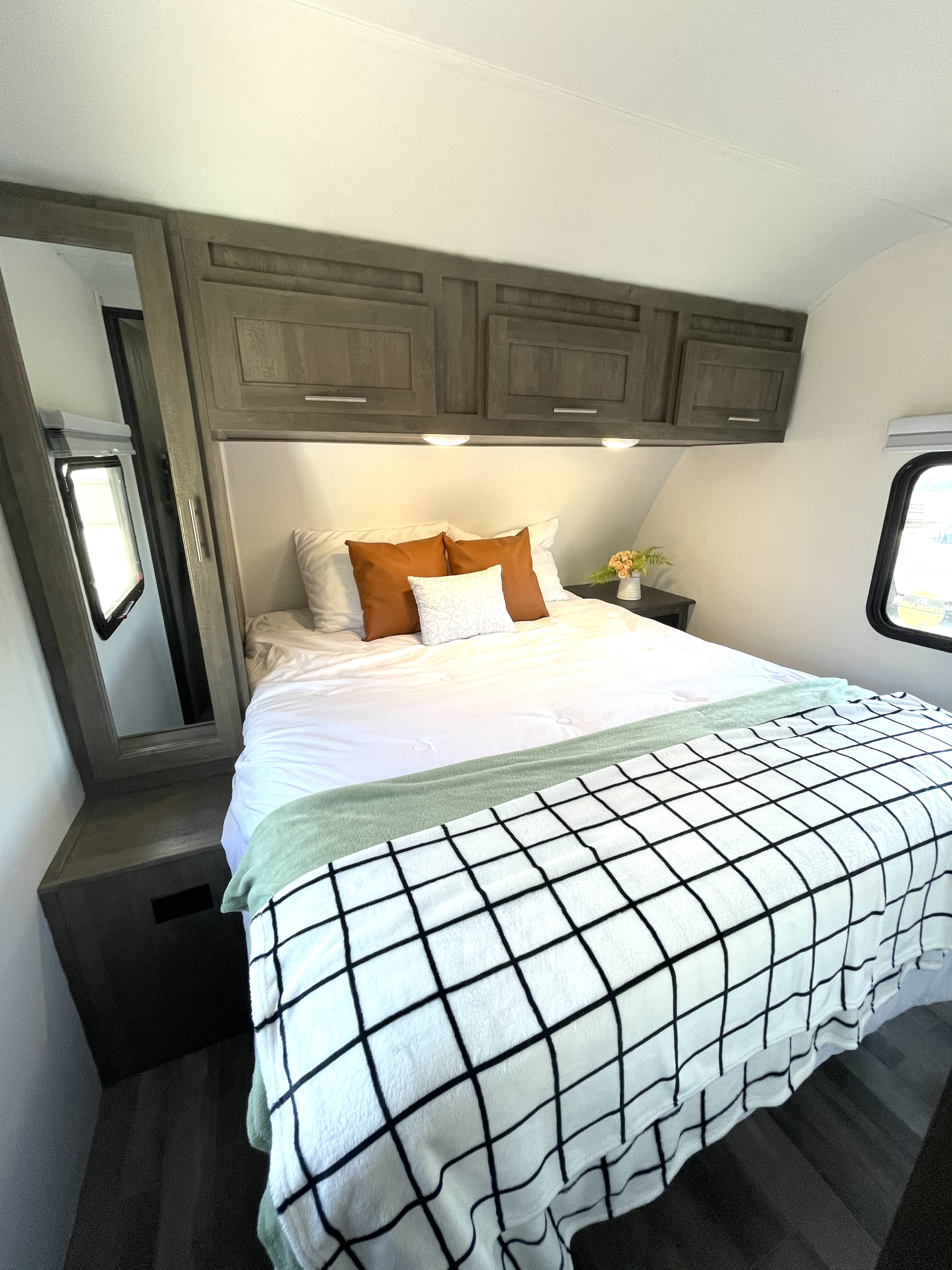 Step into comfort! This inviting RV rental bedroom features cozy bedding, ample storage, and warm lighting.. Forest River Vibe 2021