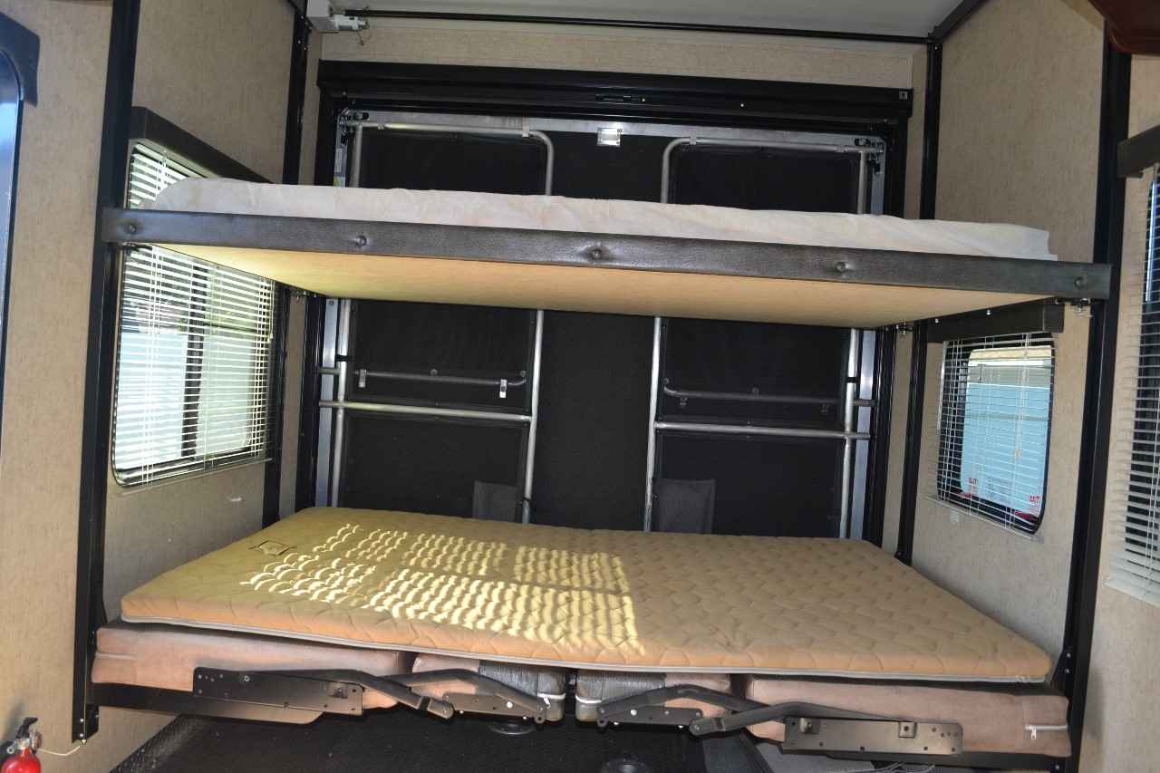 An RV rental's interior with two comfortable, drop-down bunk beds, maximizing sleeping space for adventures in a toy hauler.. Heartland Cyclone 2014