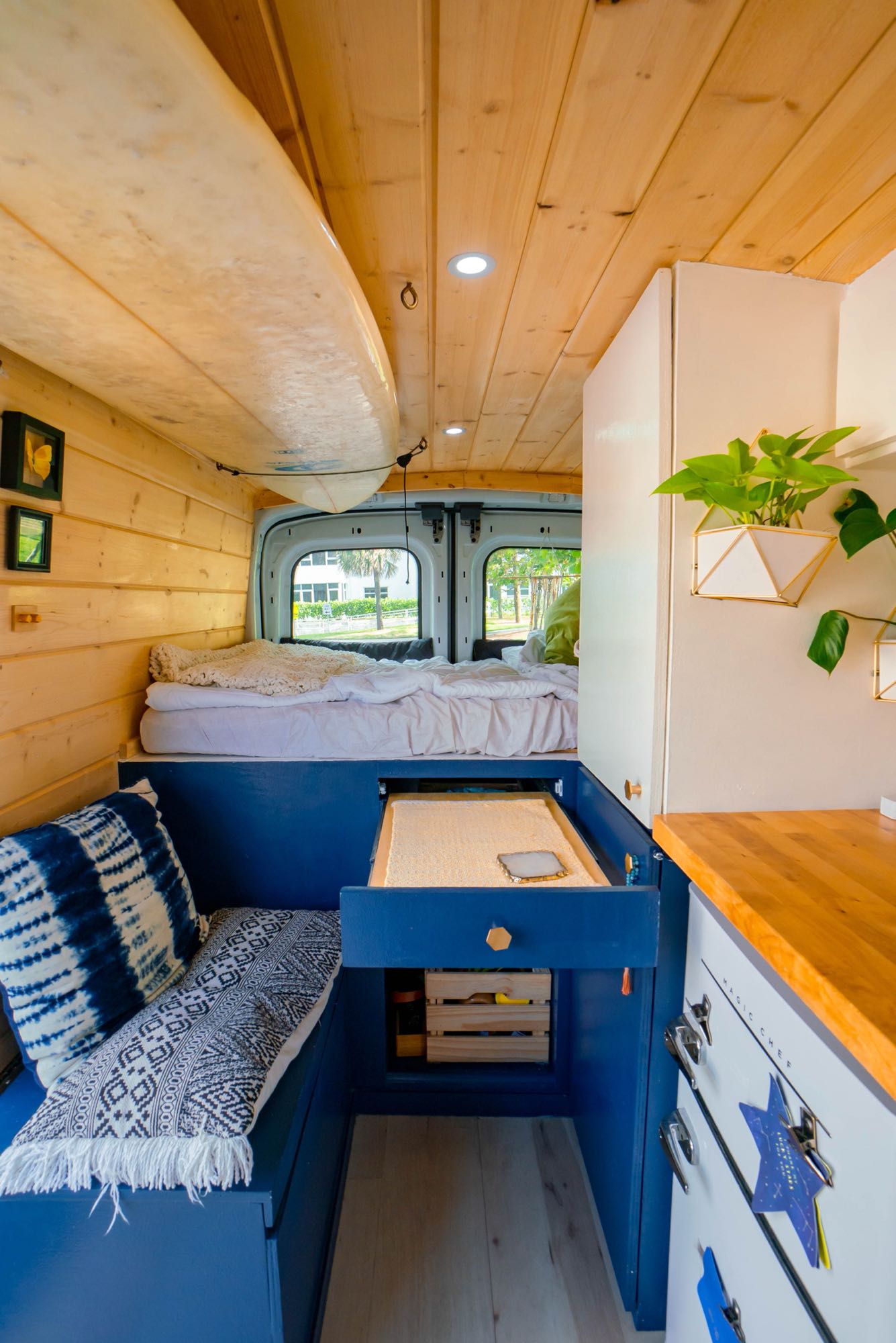 Cozy RV rental interior: a cleverly designed van conversion featuring a bed, kitchenette, and surfboard storage.. Ford Transit Custom 2020