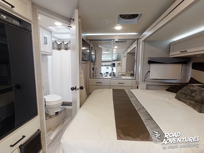 This cozy rv rental interior features a compact bedroom with a TV, mirrored closet, and an adjacent bathroom with a toilet and shower.. Thor Motor Coach Gemini 23TW 2022