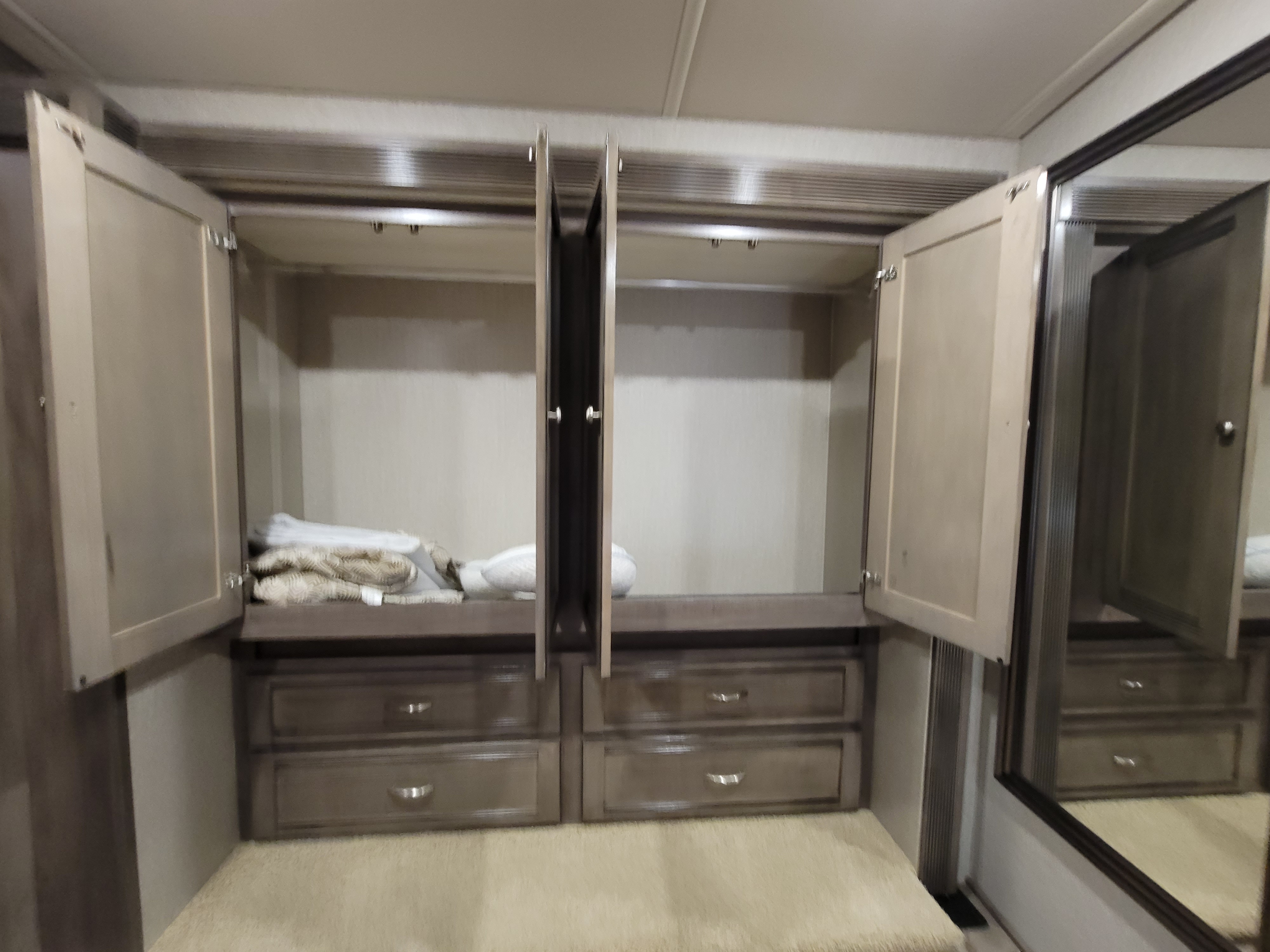 Spacious RV rental wardrobe: open cabinets, multiple drawers, and a full-length mirror for convenient storage.. Winnebago Forza 2019