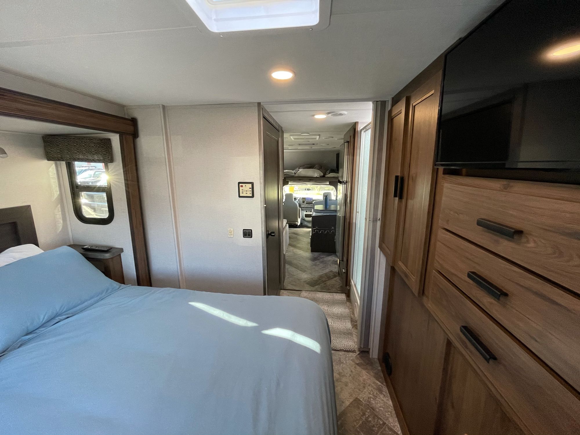 Cozy RV rental bedroom view into the living space & driver's cab. Perfect for mobile living adventures.. Forest River Sunseeker 2021